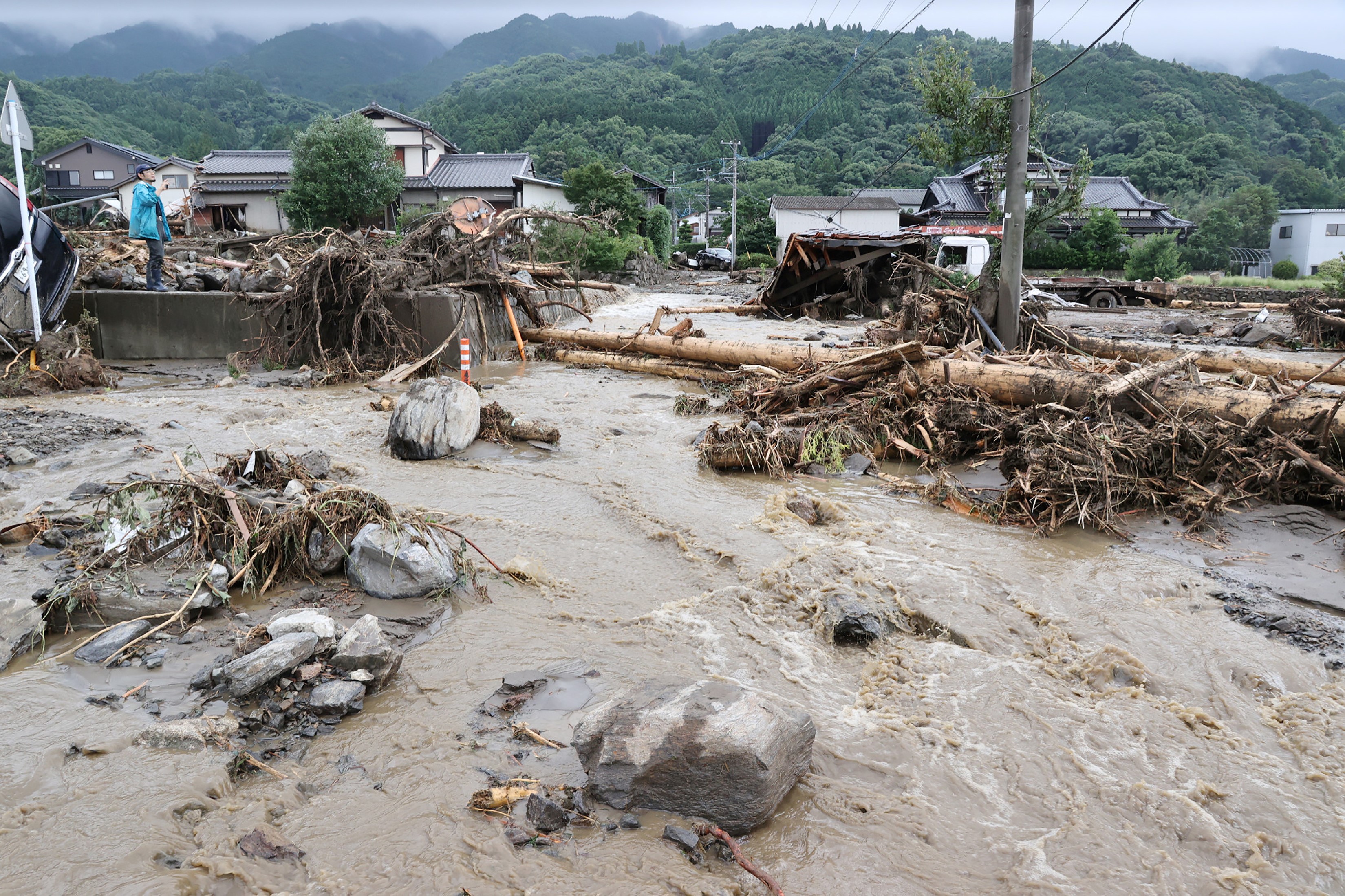 A man (L) looks at debris from flooding in the road in Tanushimarumachi in the city of Kurume