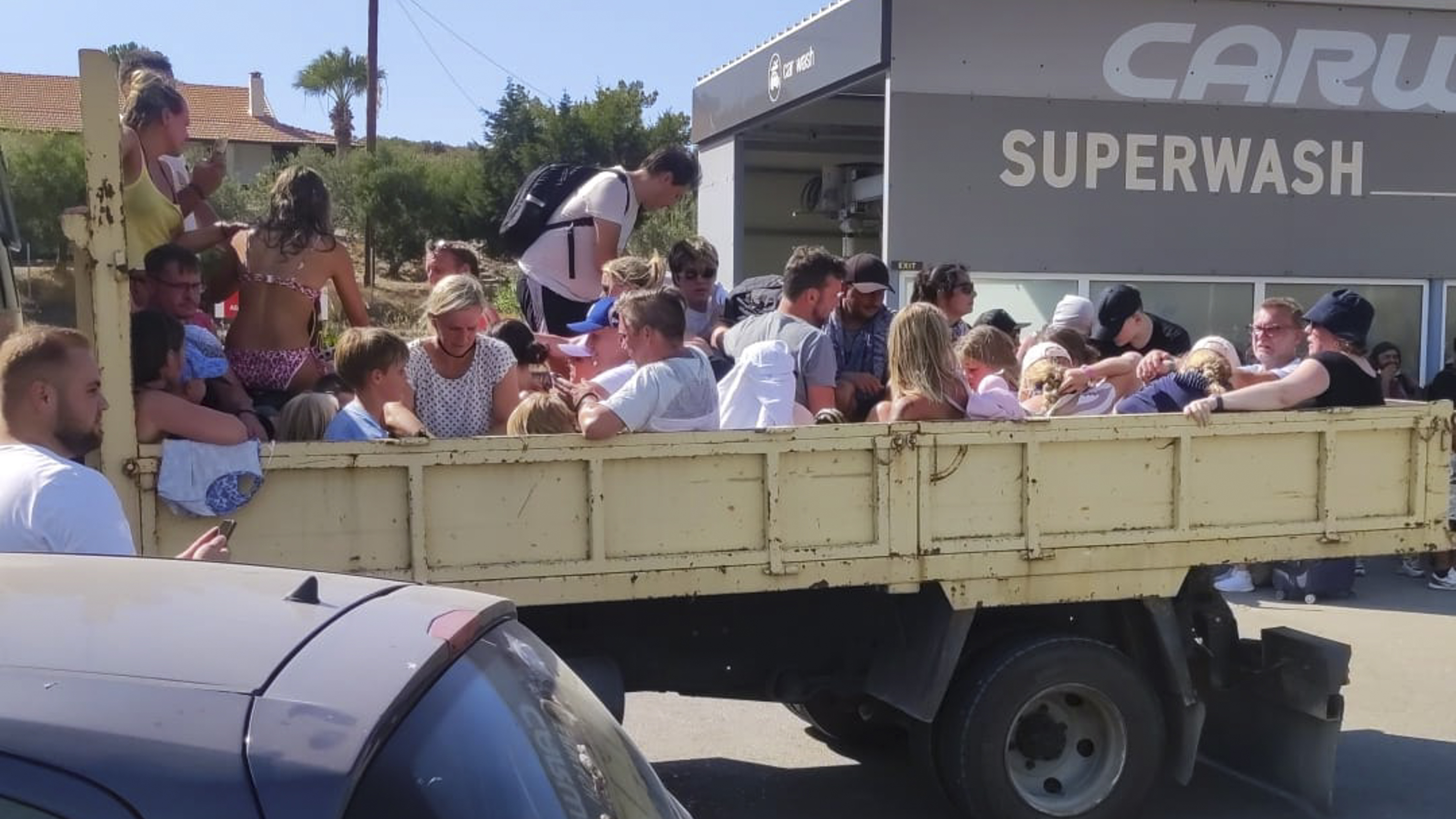 Tourists sit in the back of an open air lorry as they are evacuated