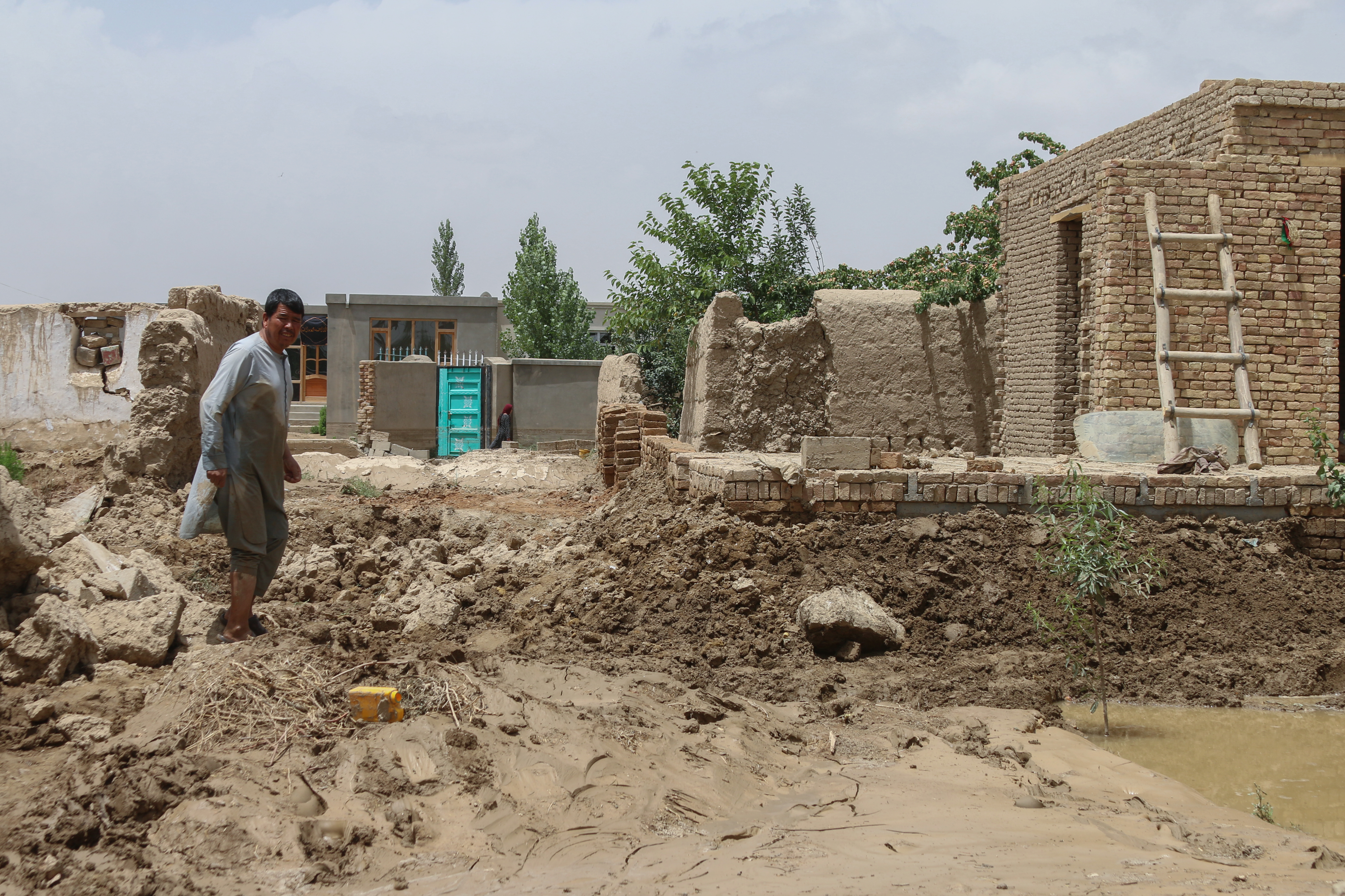 An Afghan man walks through a street covered in mud following flash floods in the Khair Abad area