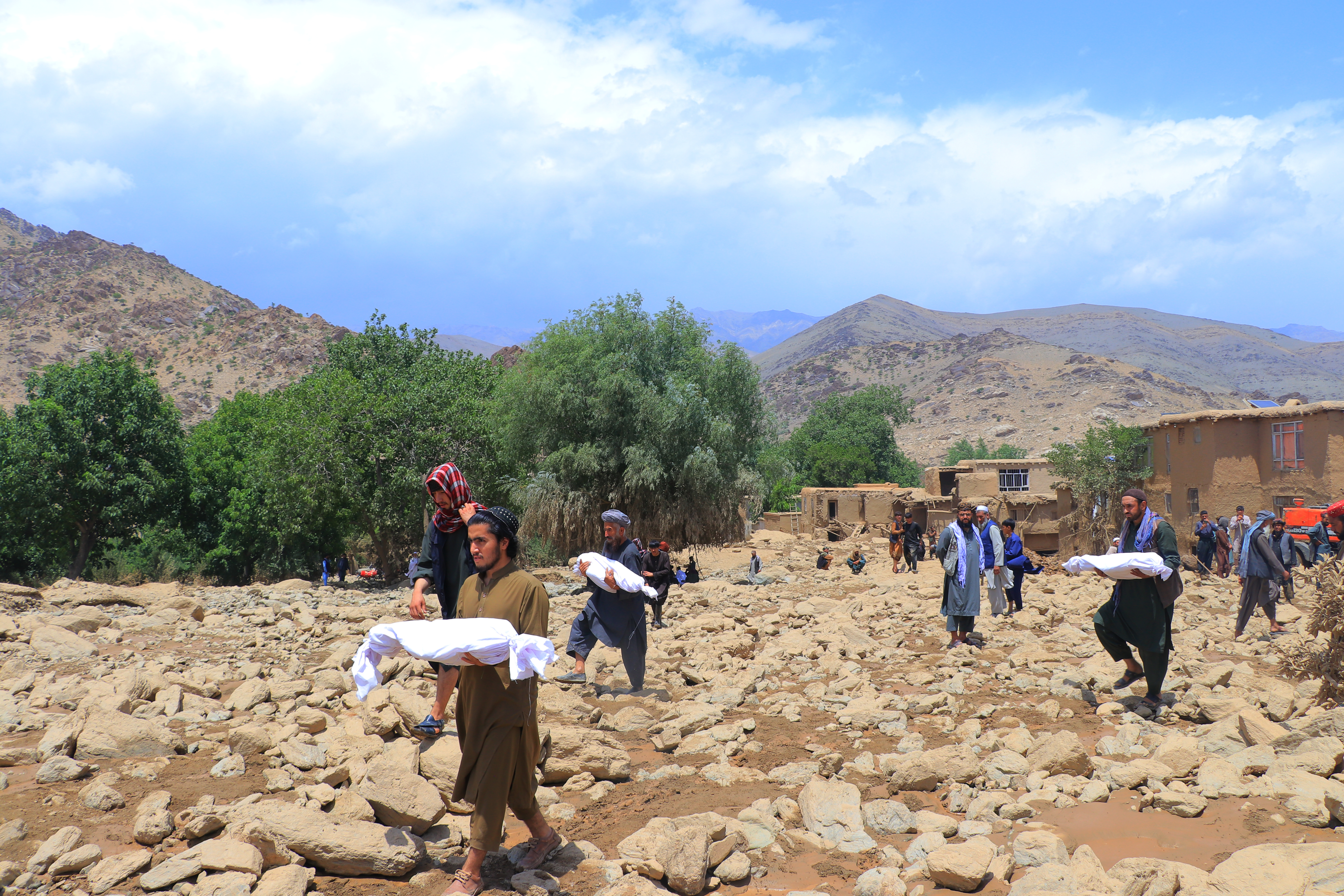 Afghan residents carry the bodies of children, who died in flash floods in the Jalrez district