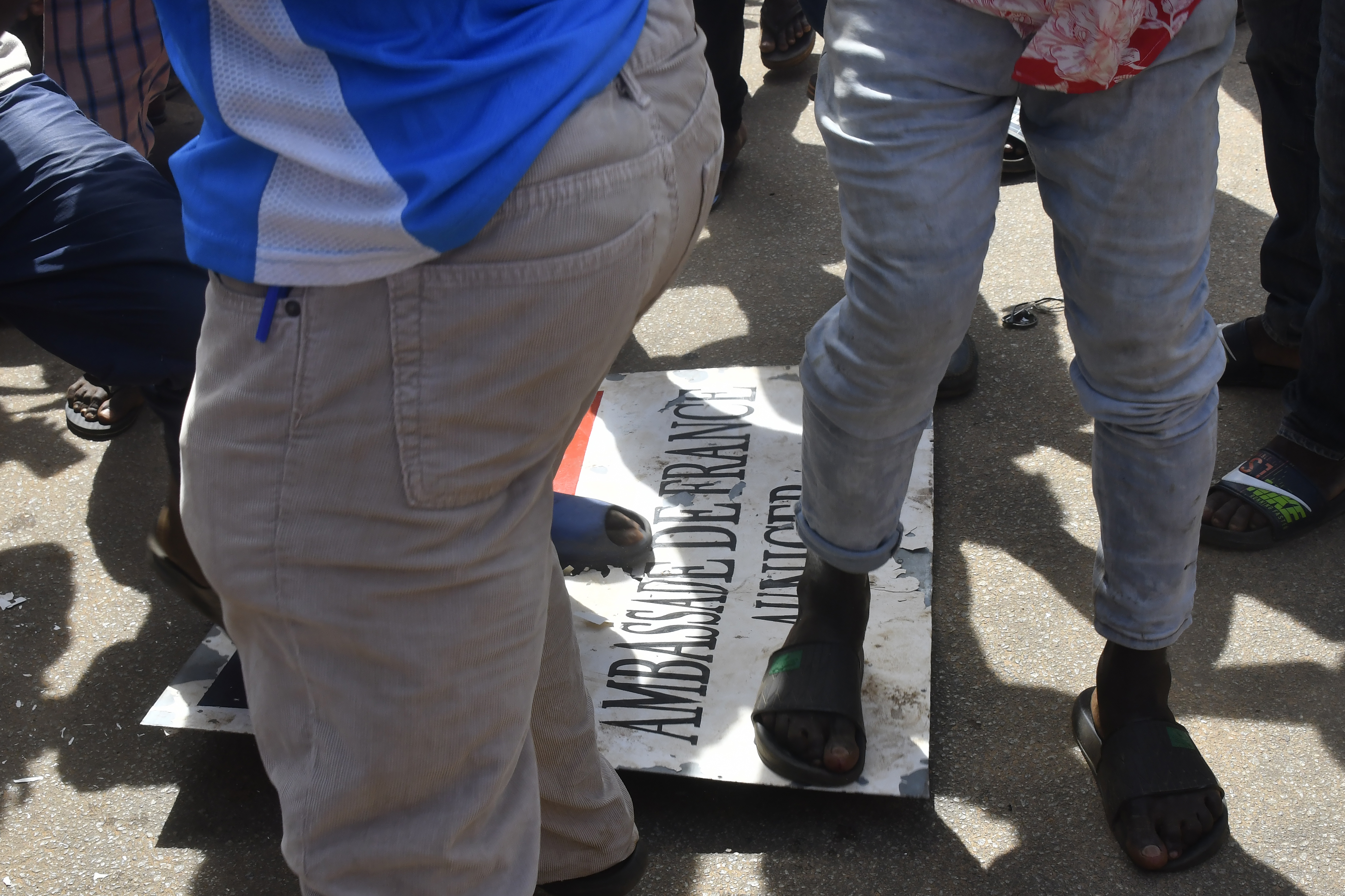 Protesters stomp over a sign taken from the French Embassy