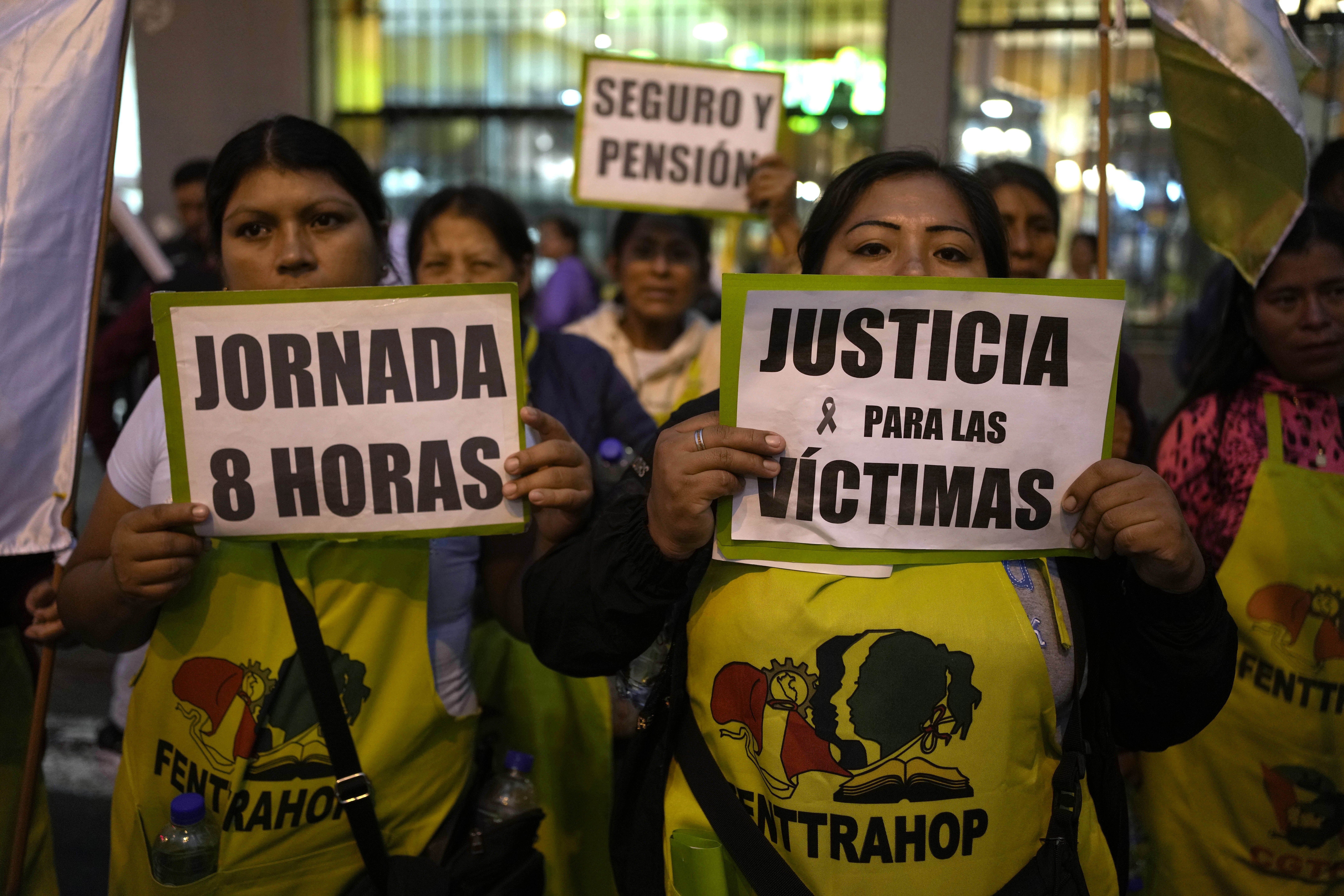 People dressed in yellow shirts hold up signs that read, "Jornada 8 horas" and "Justicia para las victimas"