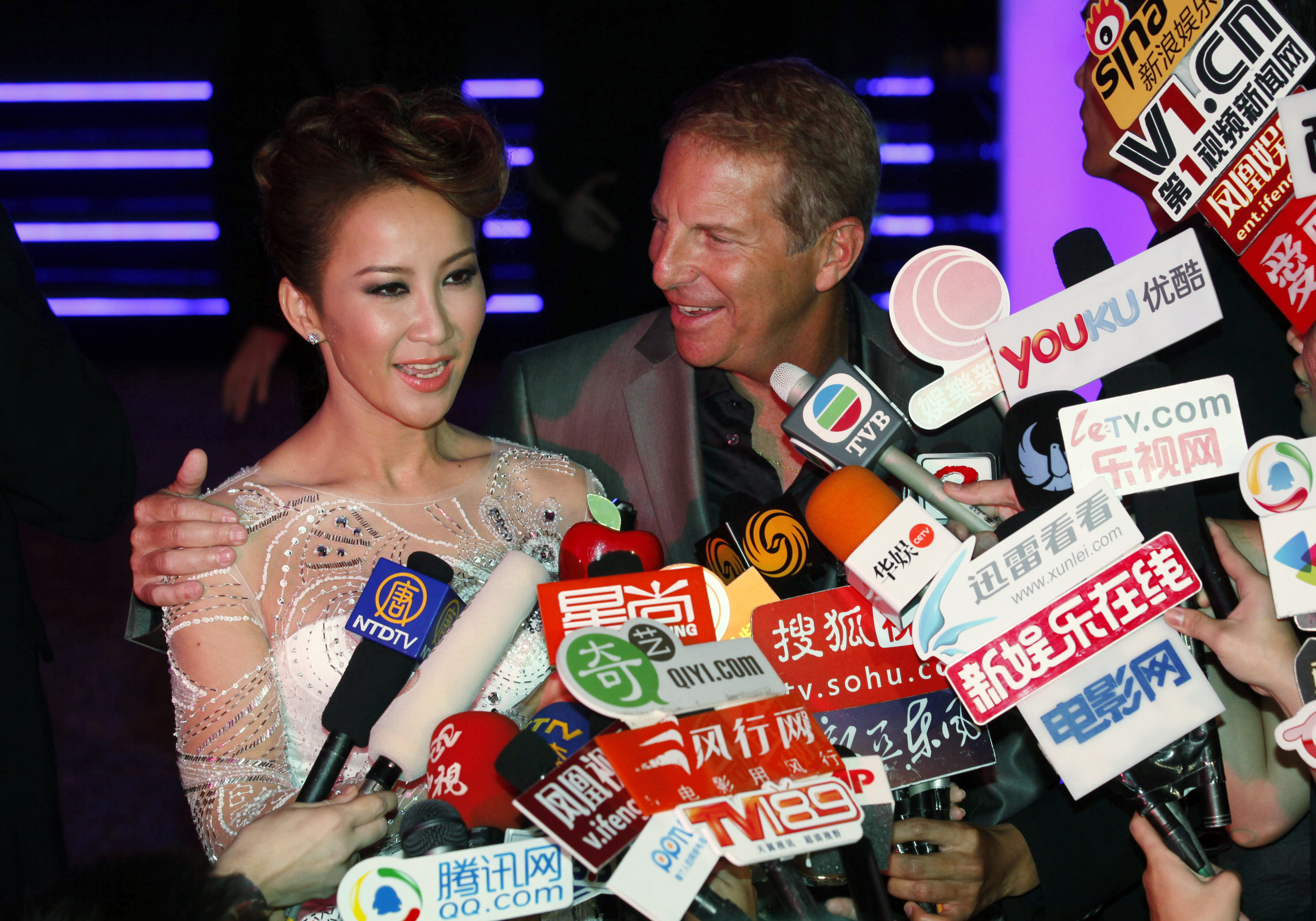 Coco Lee and her husband Bruce Rockowitz, speak to the media at their wedding banquet in 2011. There is a bank of microphones in front of them. They both look very happy.