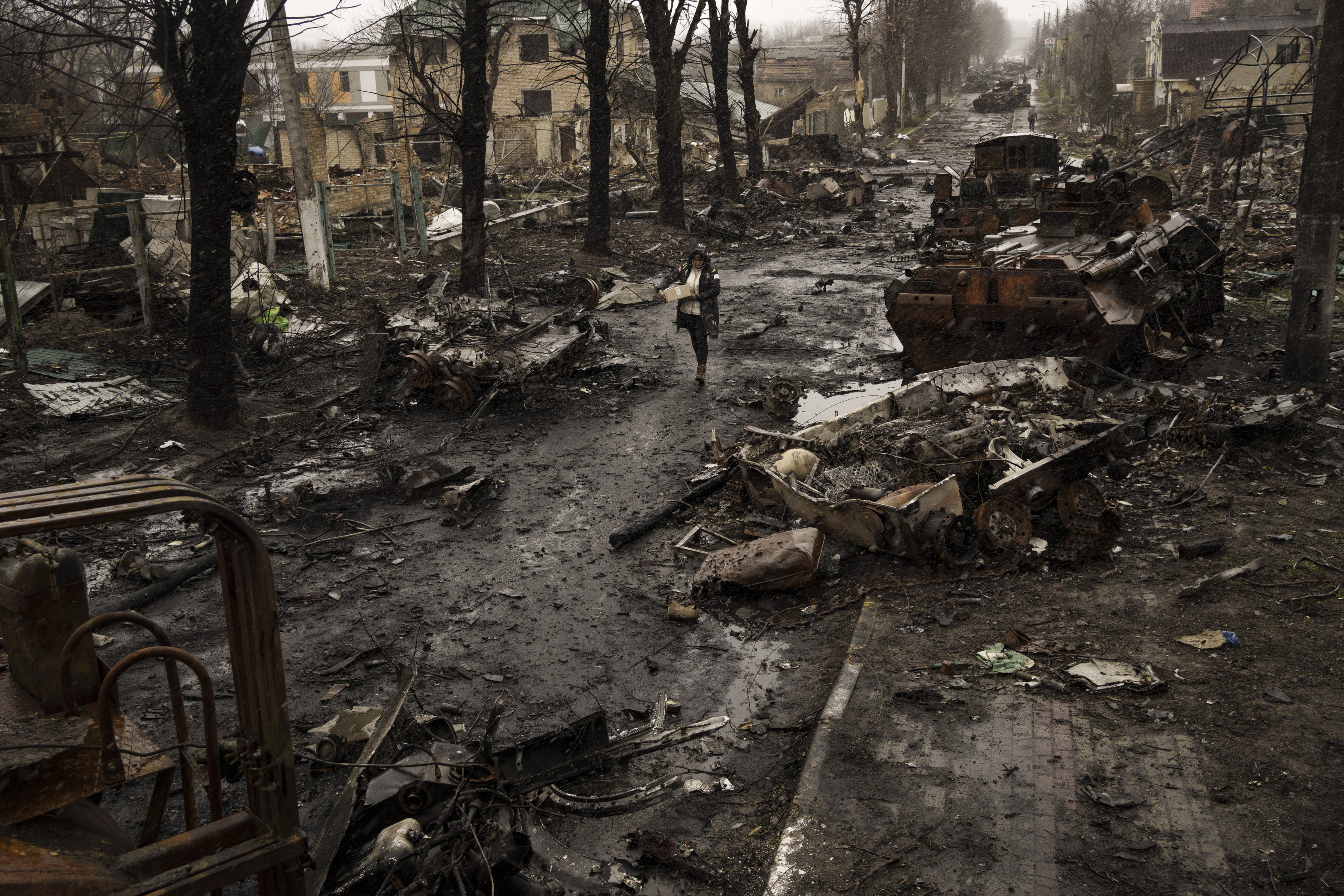 A woman walks amid destroyed Russian tanks in Bucha, in the outskirts of Kyiv