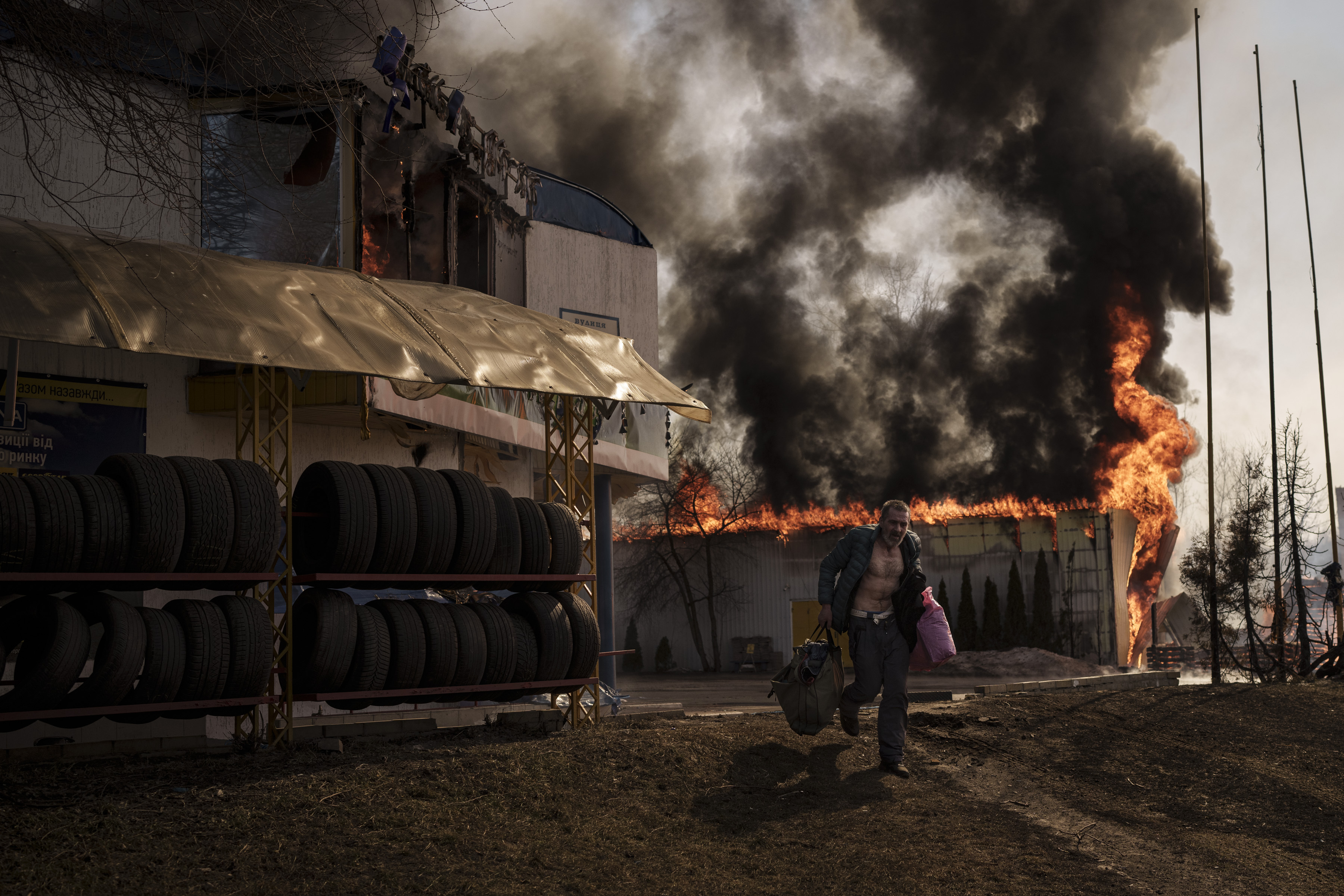 A man runs while recovering items from a burning shop following a Russian attack in Kharkiv