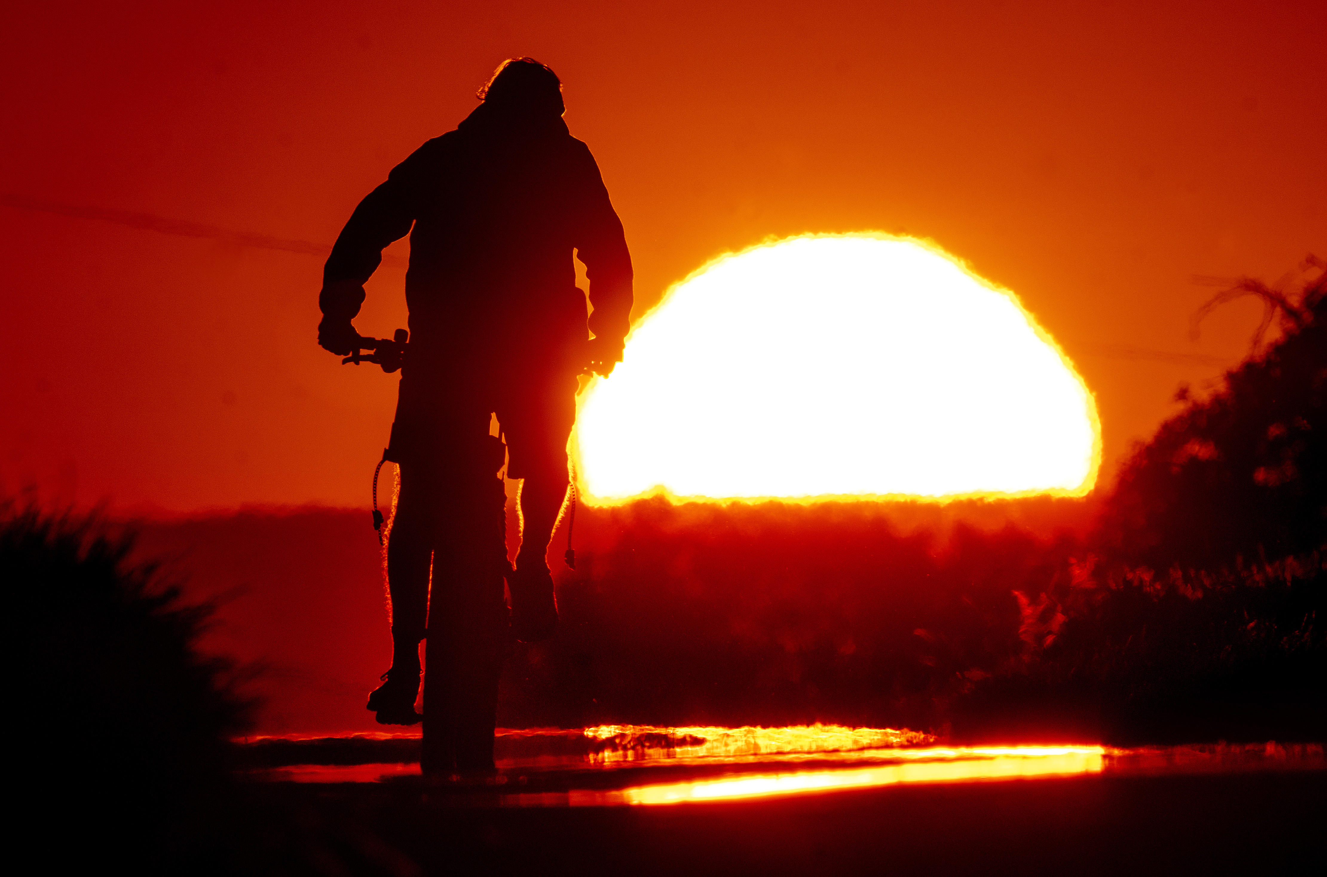 A man rides a bike on a small road on the outskirts of Frankfurt, Germany, as the sun rises
