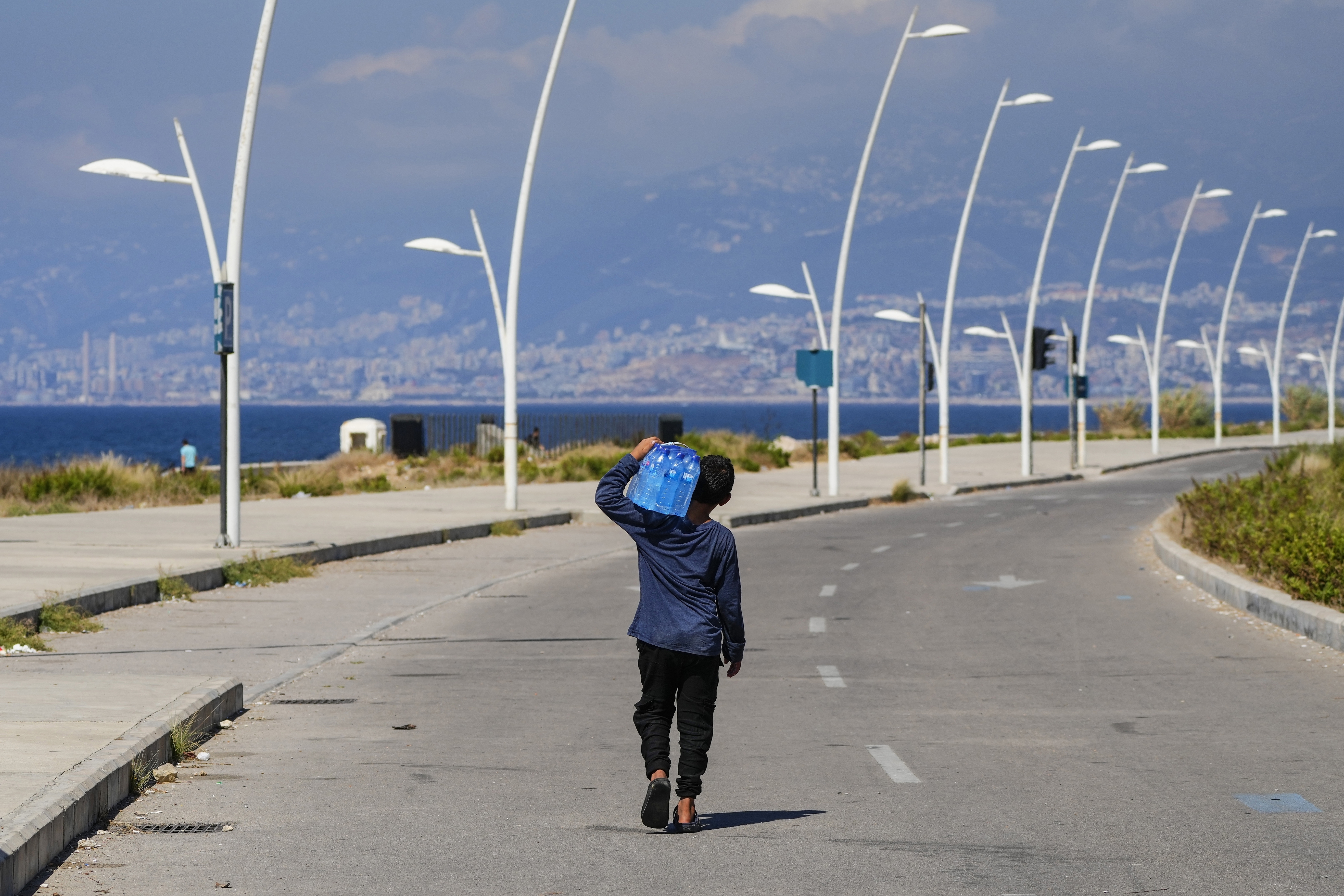 A young street vendor carries a pack of water bottles as he looking for customers
