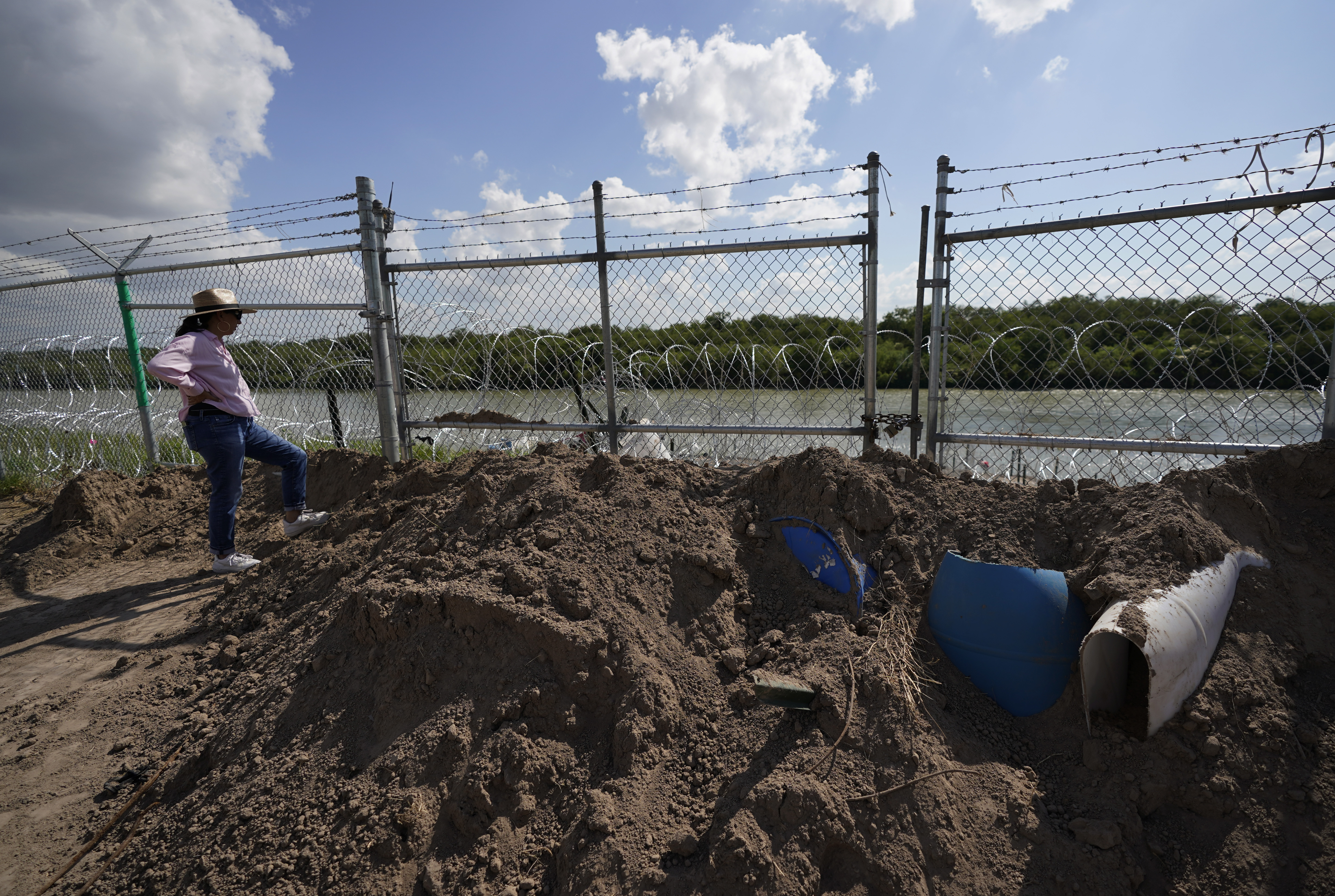 Magali Urbina stands near a gate on pecan farm that has been bulldozed, locked and lined with concertina