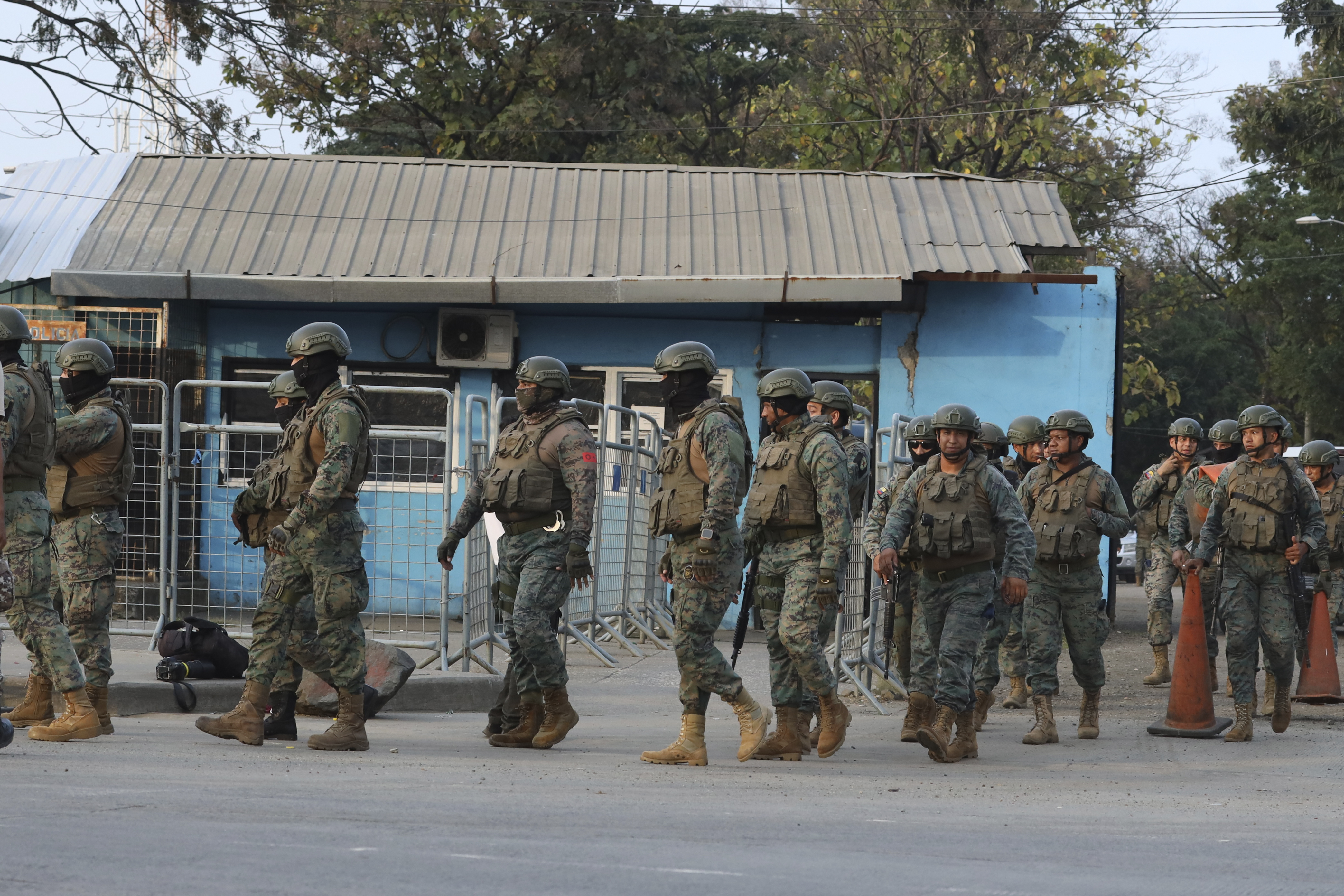 A line of soldiers stand in front of a one-story blue building.