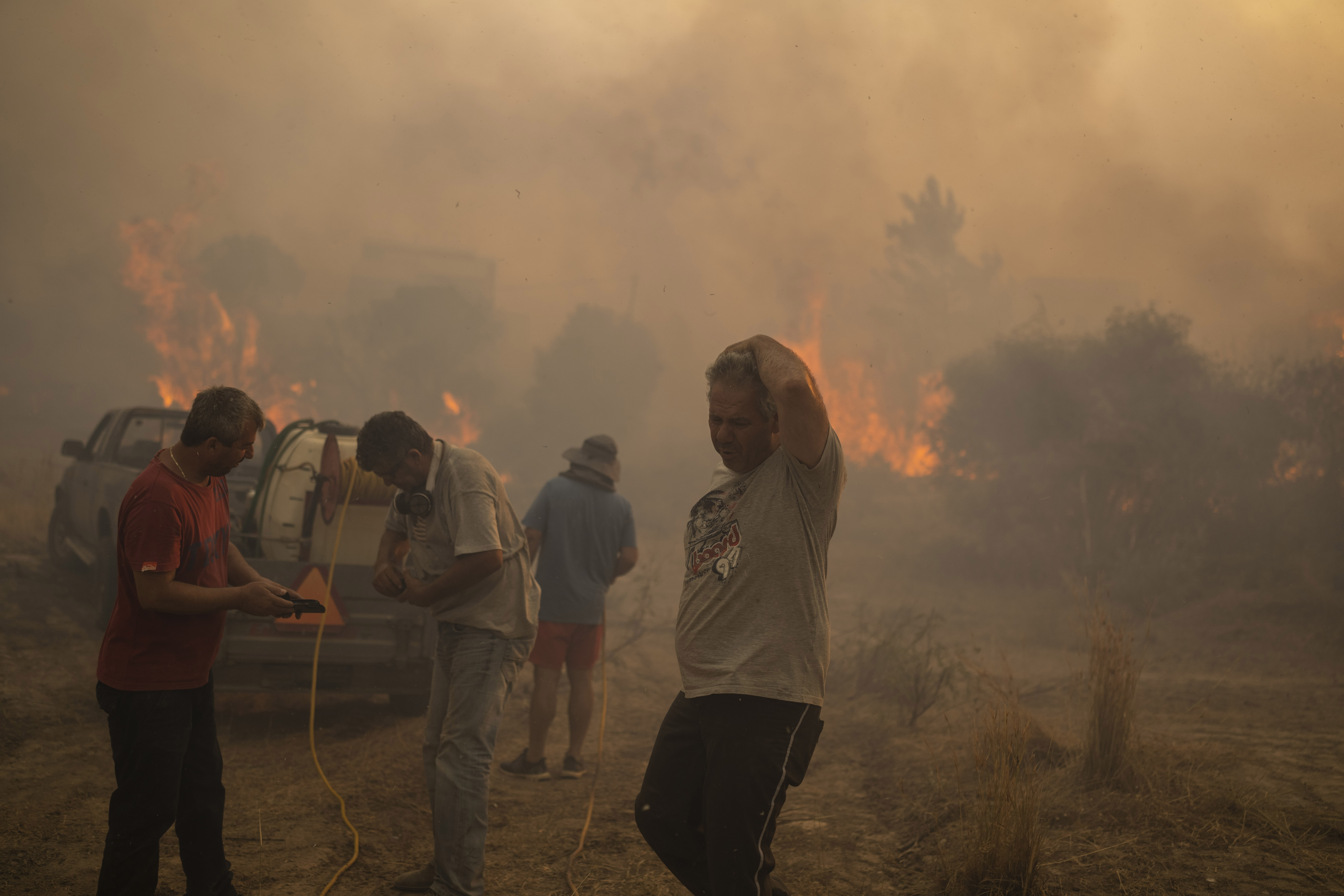 Locals try to extinguish a wildfire burning in Gennadi village, on the Aegean Sea island of Rhodes
