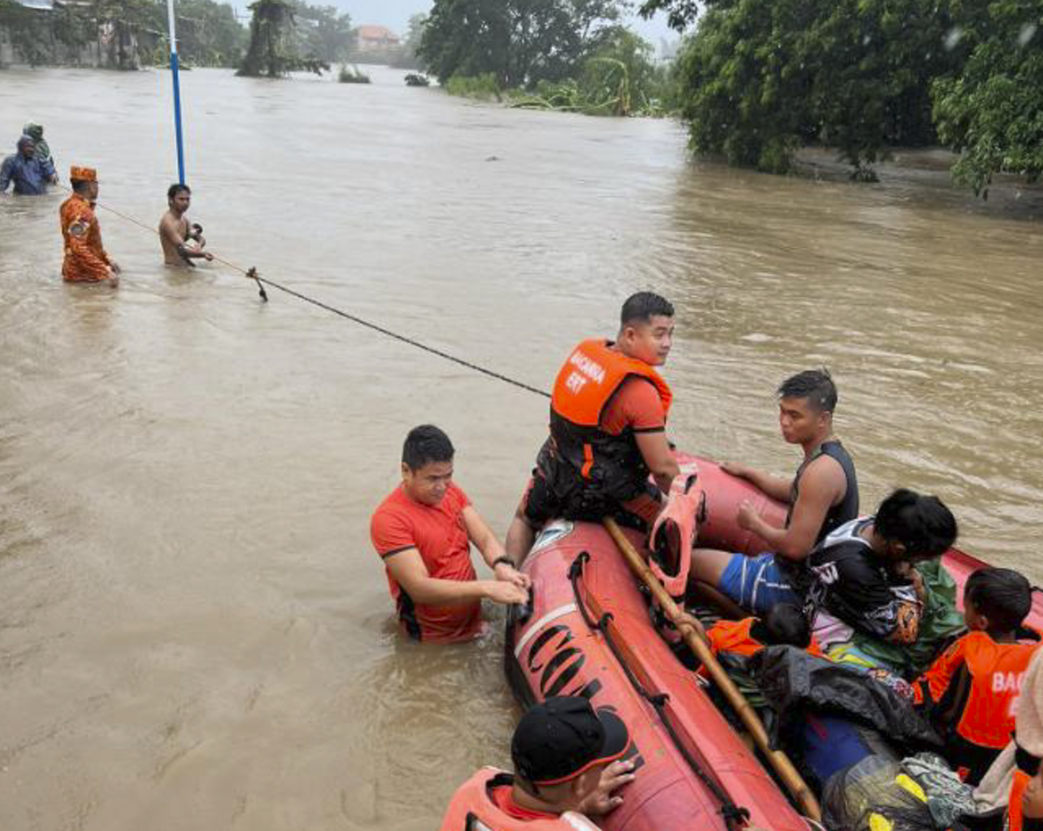 Rescuers use a rubber boat along floodwaters caused by Typhoon Doksuri as they evacuate residents to higher grounds in Bacarra, Ilocos Norte province, northern Philippines on Wednesday July 26, 2023.