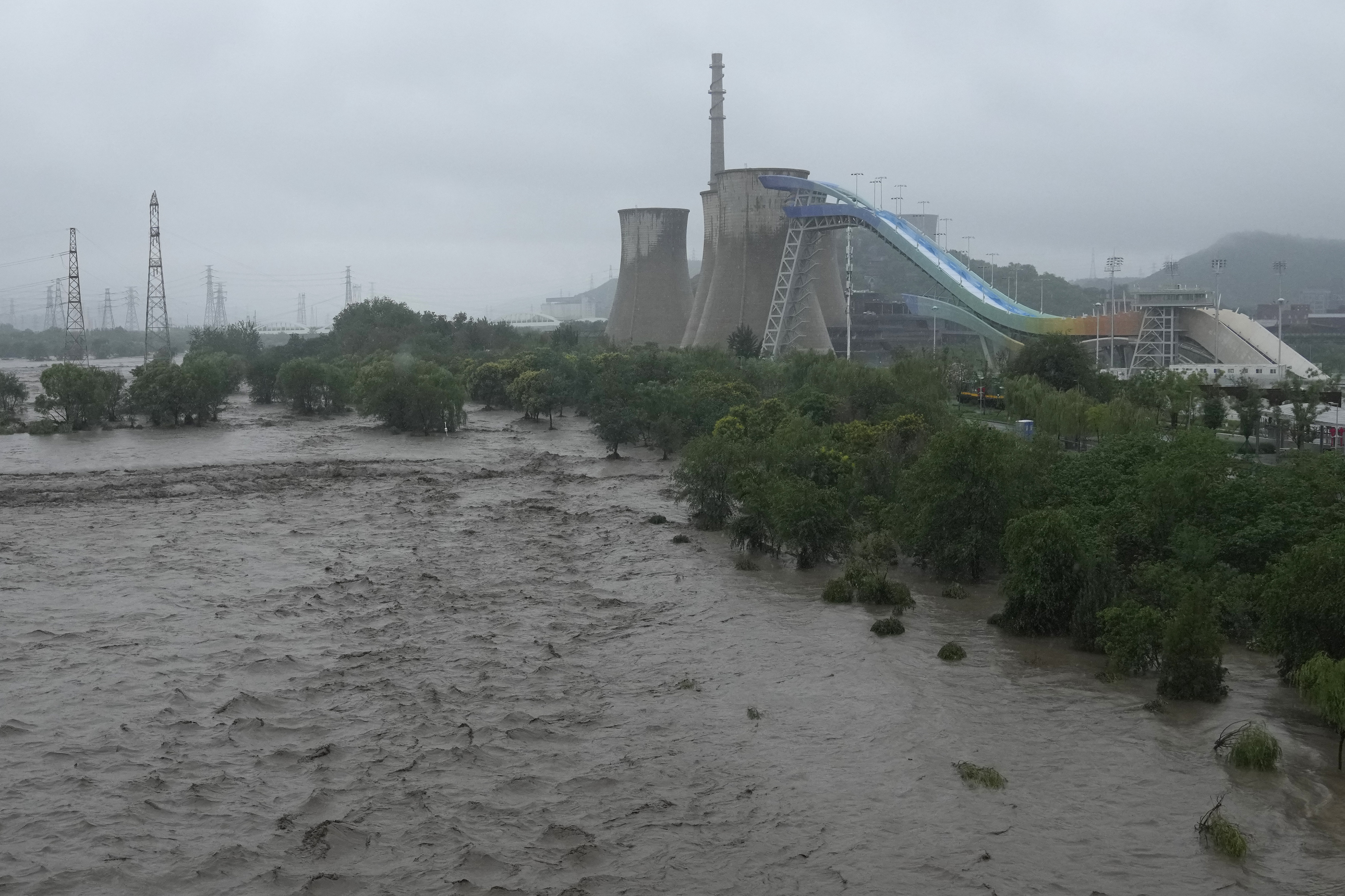 A swollen Yongding river floods the banks near the Shougang park