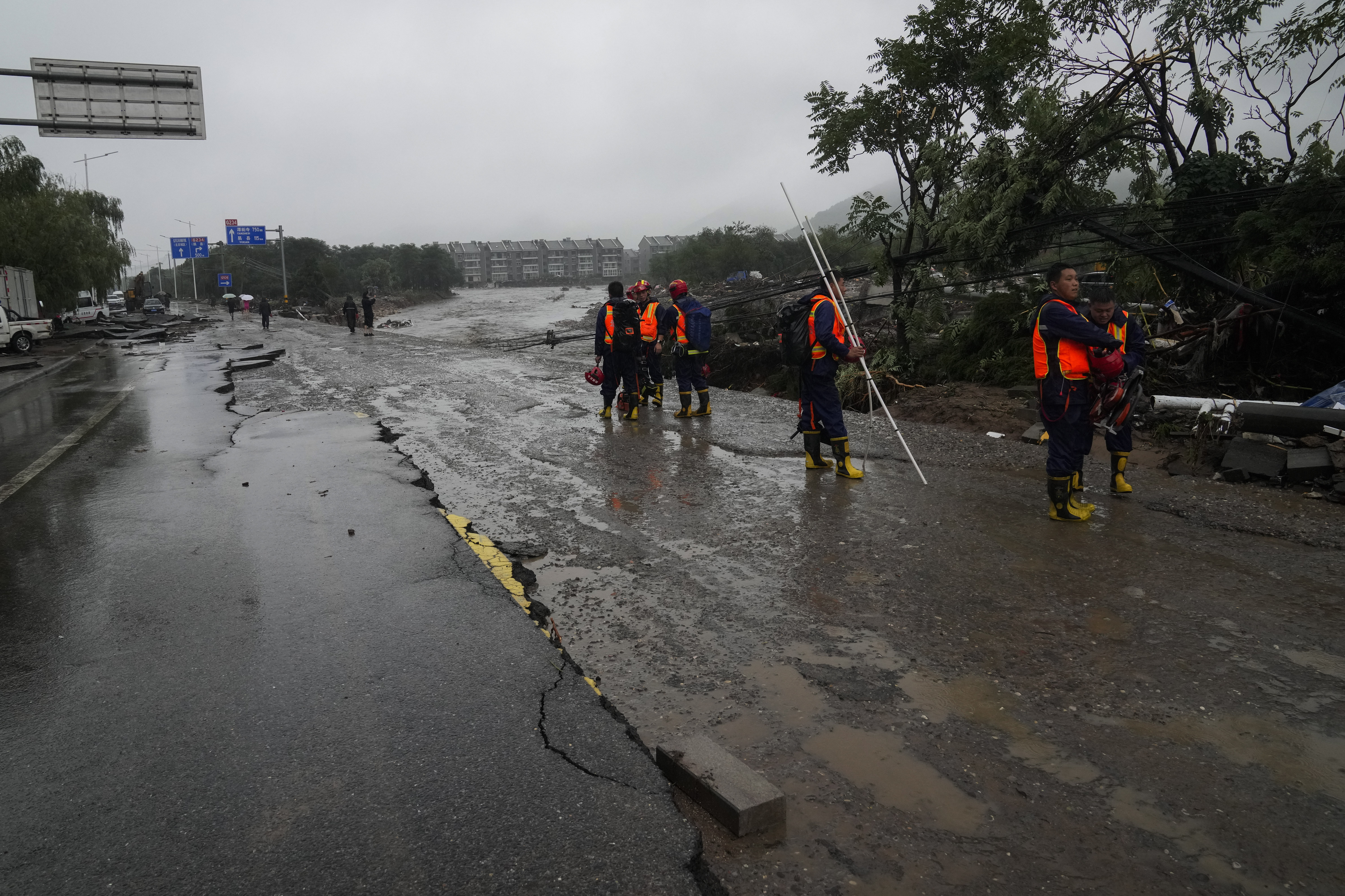 Rescue workers arrive to a village near a riverbank damaged by flood water