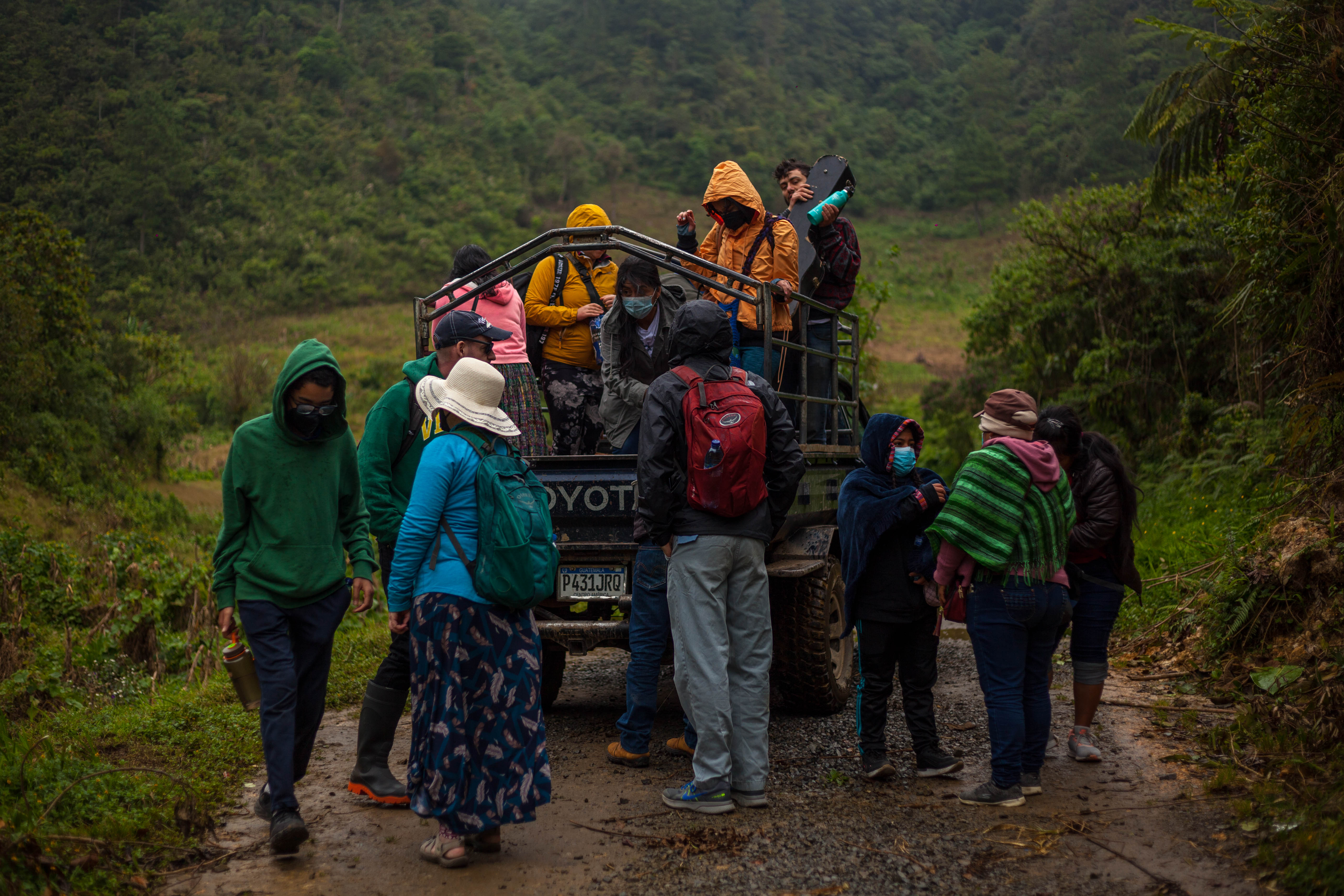 A group of Indigenous people push a cart up a dirt path
