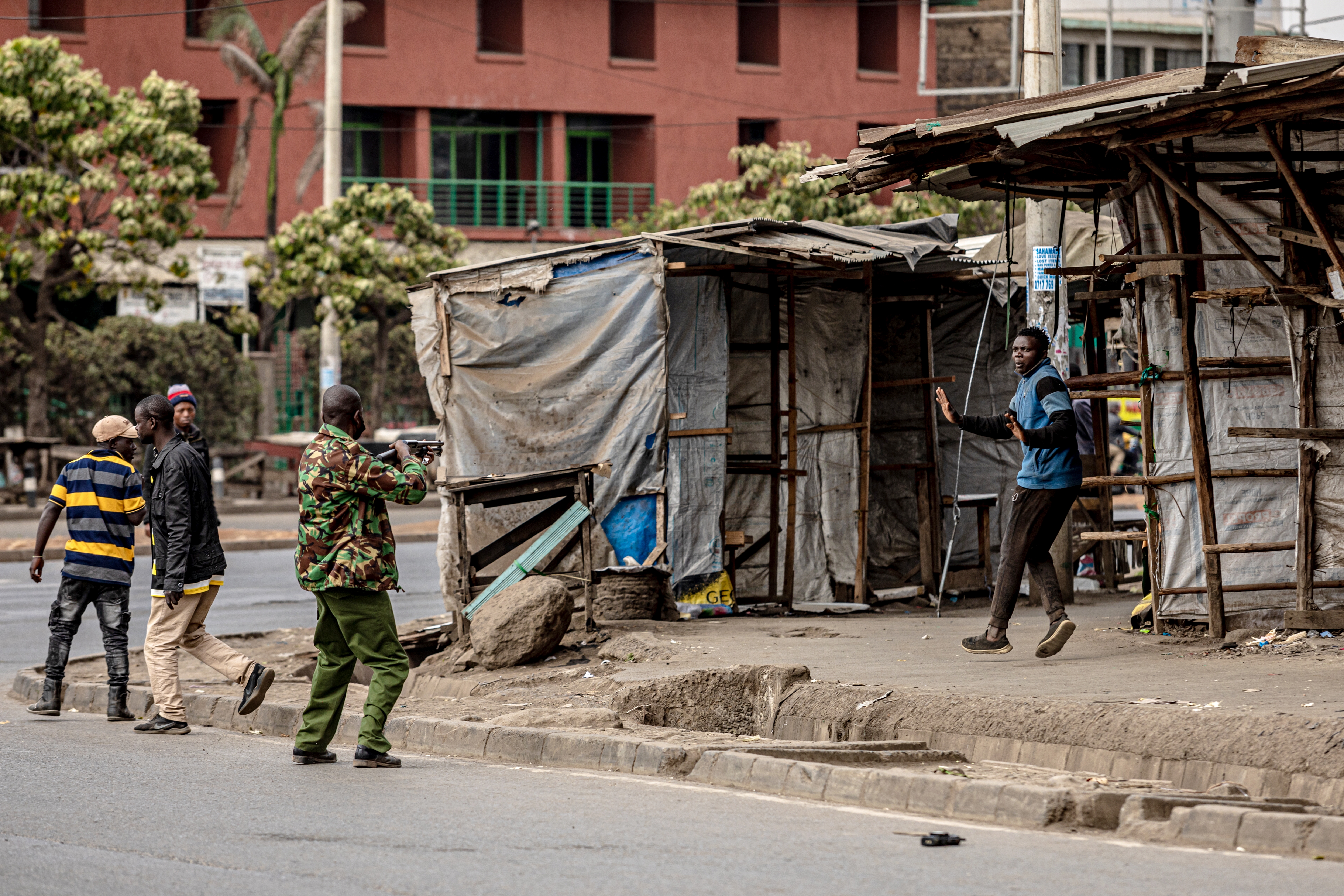 A protester raises his hands as a police officer aims his gun at him during anti-government protests in Nairobi.