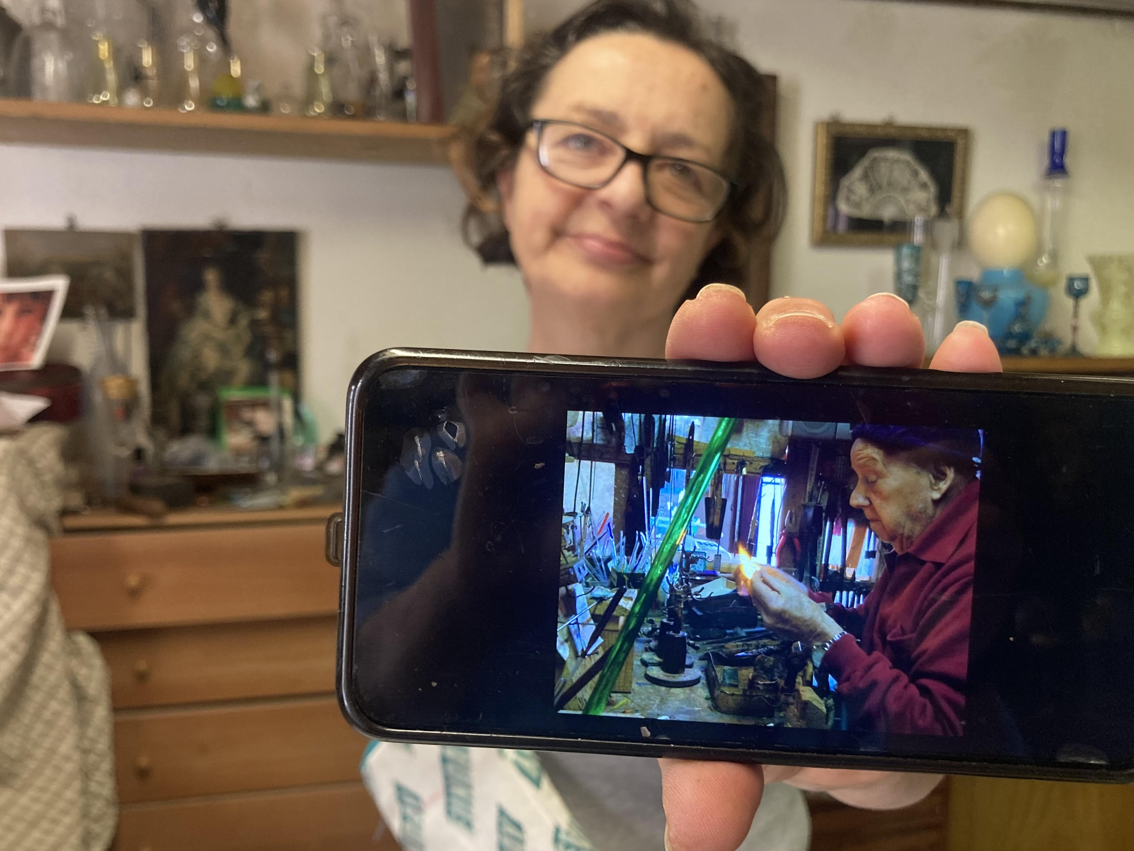 A woman holds up her phone with a picture of her father
