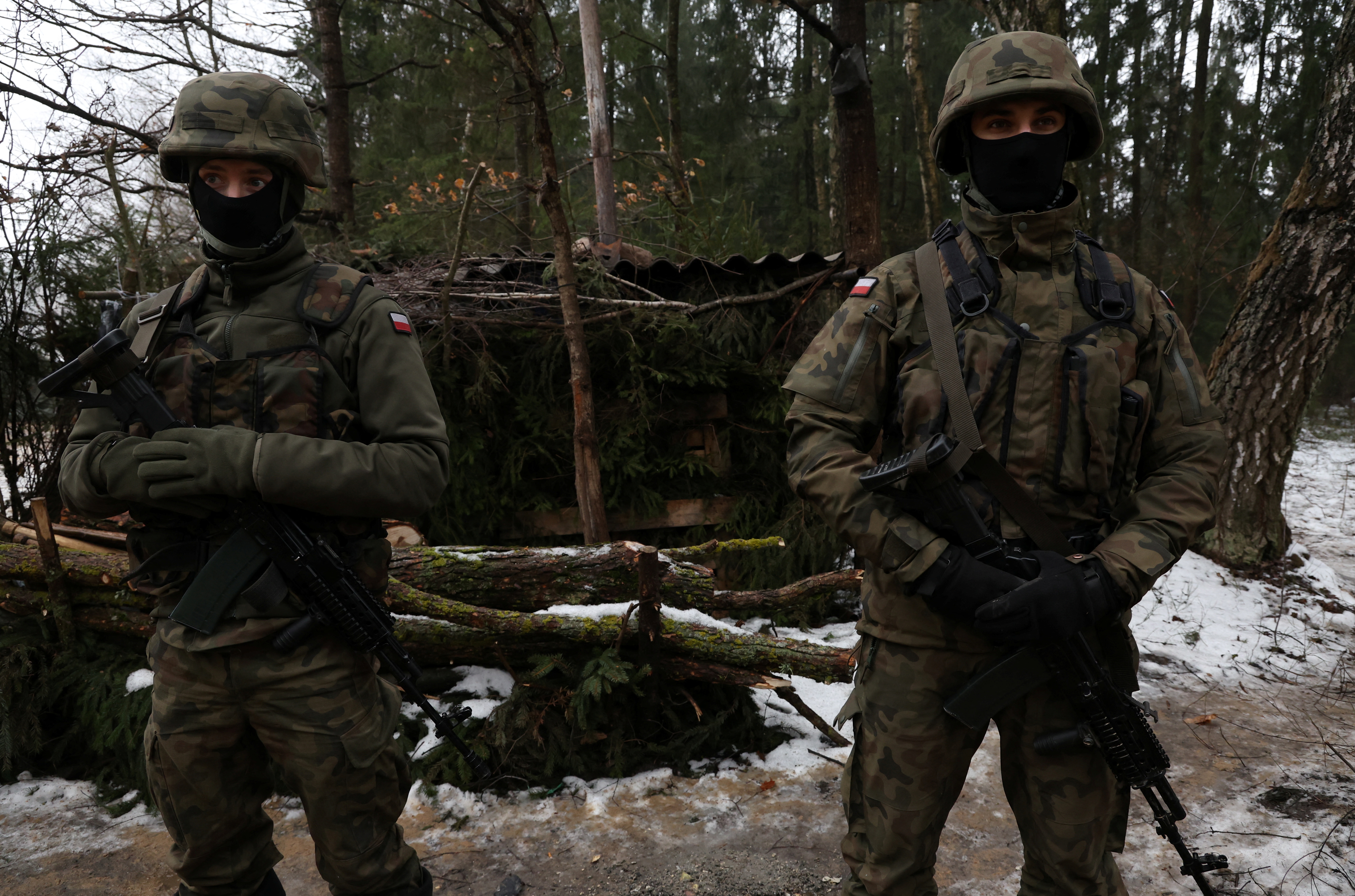 Soldiers keep watch at the construction site of a barrier at the border between Poland and Belarus