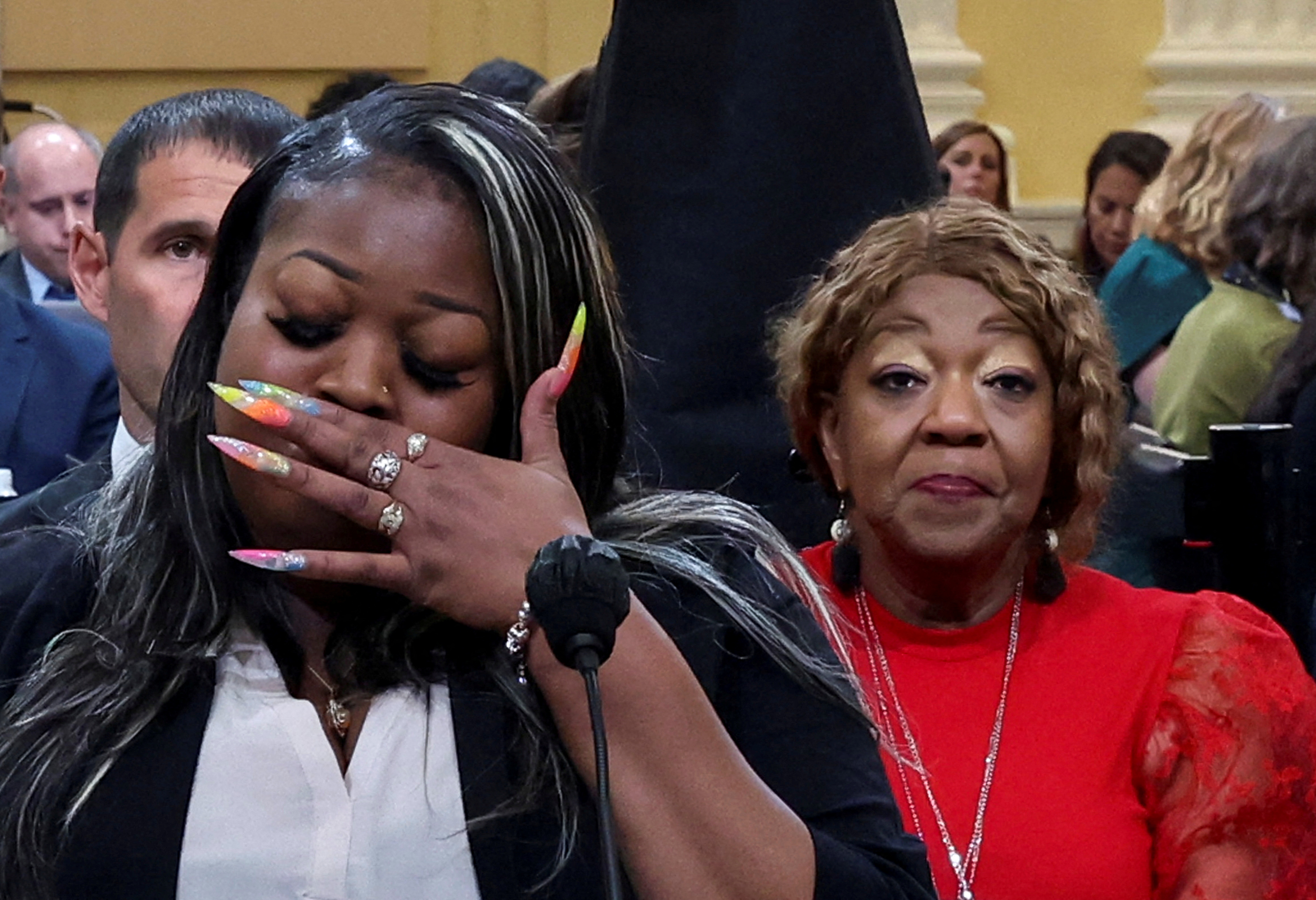 Wandrea "Shaye" Moss covers her mouth with her hand as she starts to get emotional during her testimony, with her mother Ruby Freeman sitting behind her in support.