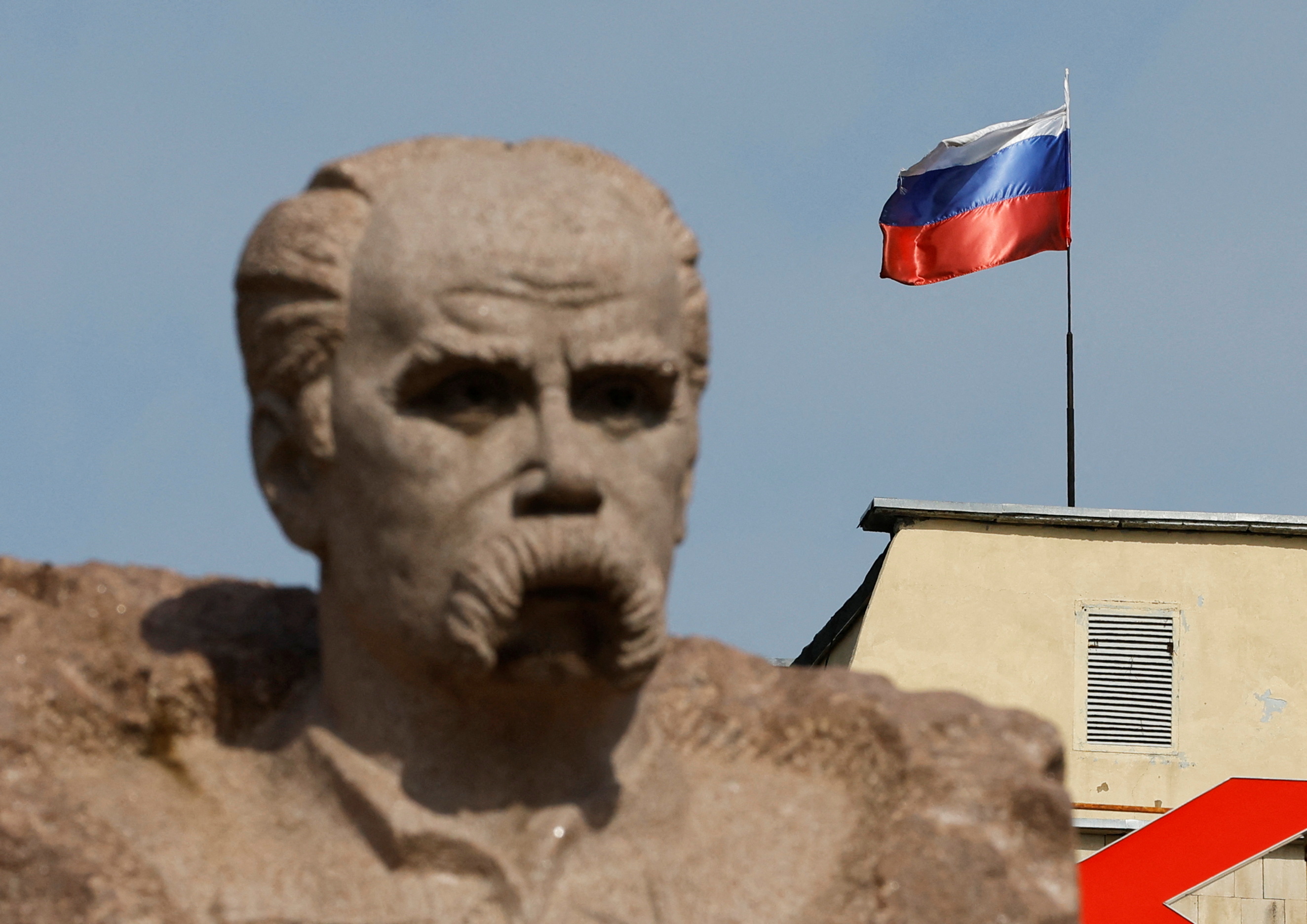 The Russian flag flies on the top of a building, as a monument to Ukrainian poet Taras Shevchenko is seen in the foreground, in the course of Ukraine-Russia conflict in the Russian-controlled city of Enerhodar in Zaporizhzhia region, Ukraine August 22, 2022. REUTERS/Alexander Ermochenko