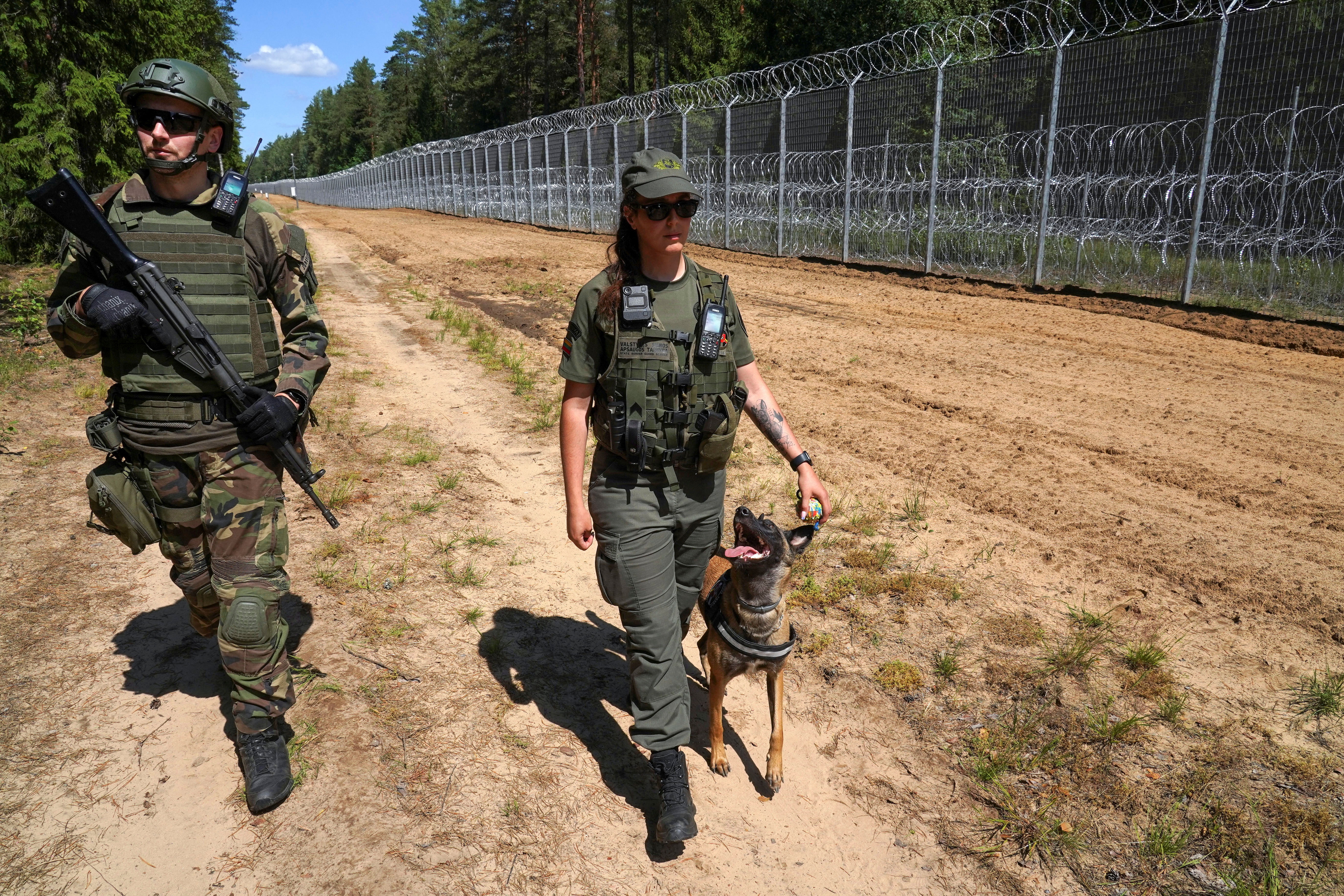 A member of Lithuanian Riflemen's Union and a Border Guard officer patrol along Belarus border in Kaniukai, Lithuania July 7, 2023. REUTERS/Janis Laizans
