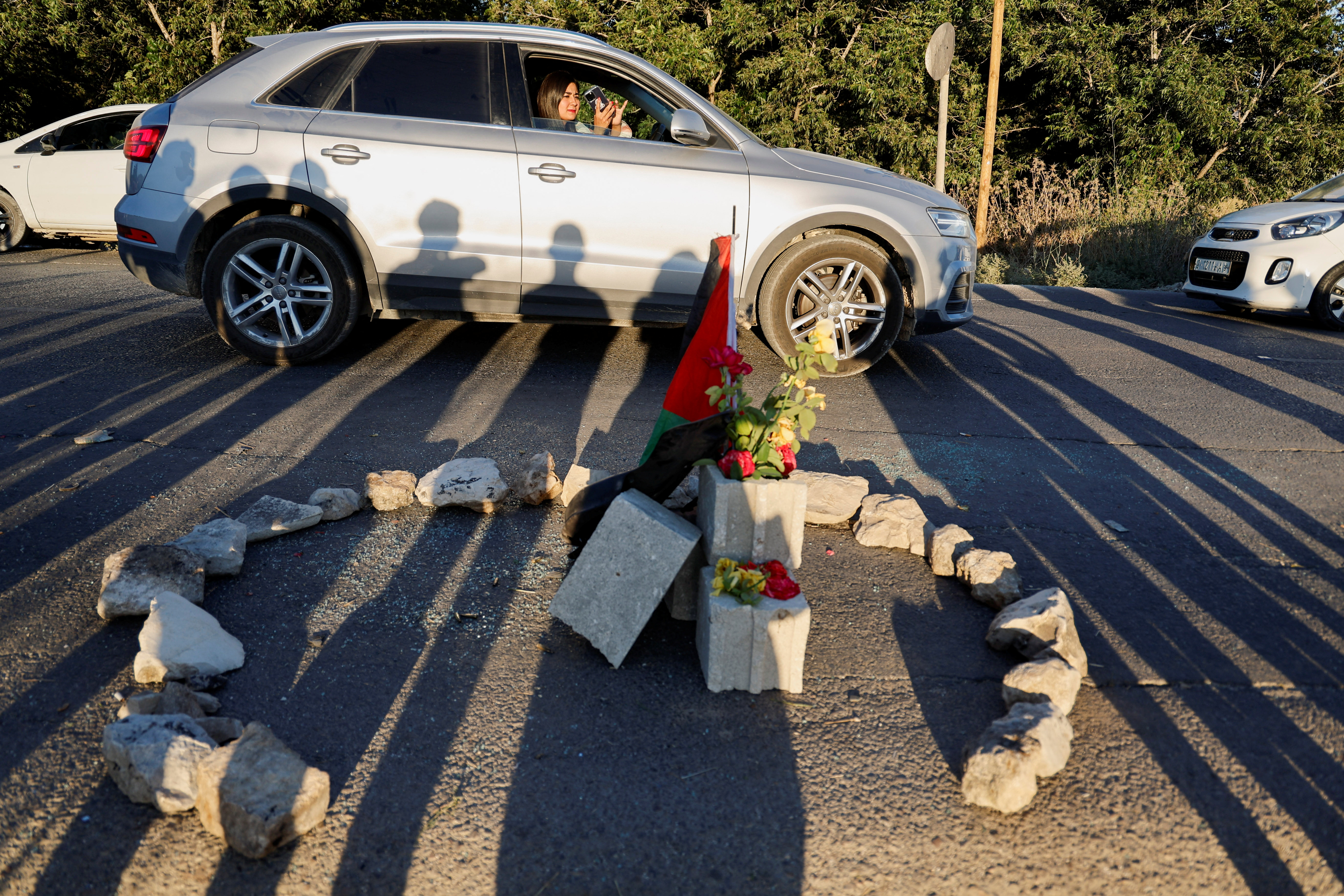 A woman passes in a car by the scene where Israeli forces targeted a Palestinian car, near Jenin