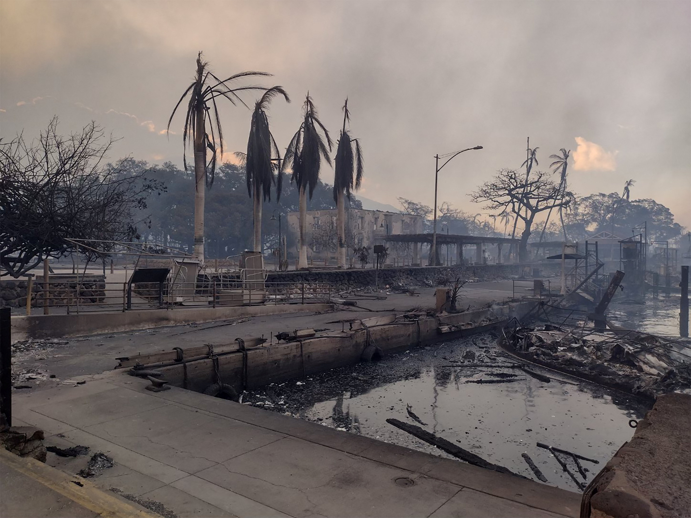 A charred boat lies in the scorched waterfront in Lahaina, Hawaii, after wildfires