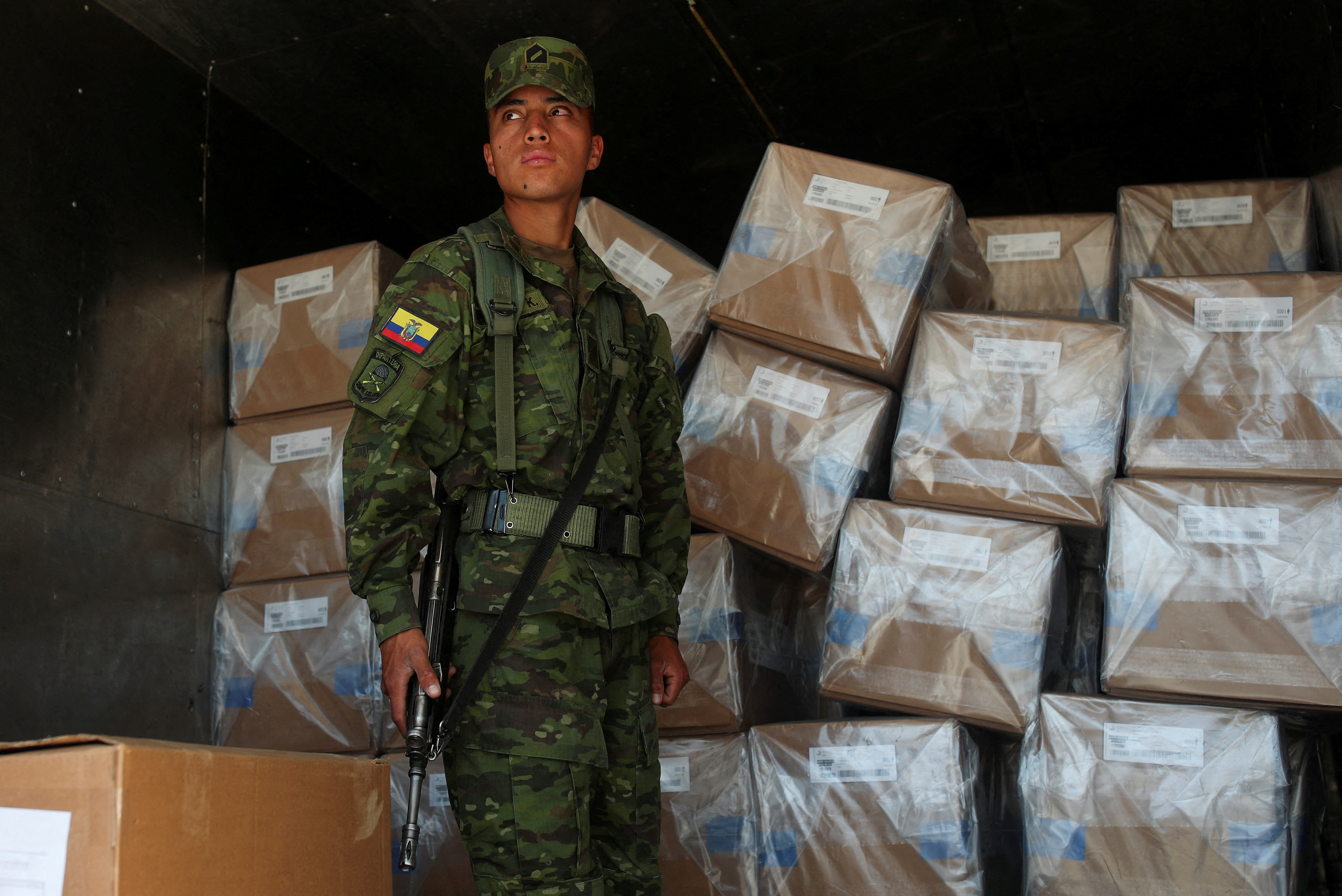 A soldier stands guard next to ballot boxes in Ecuador.