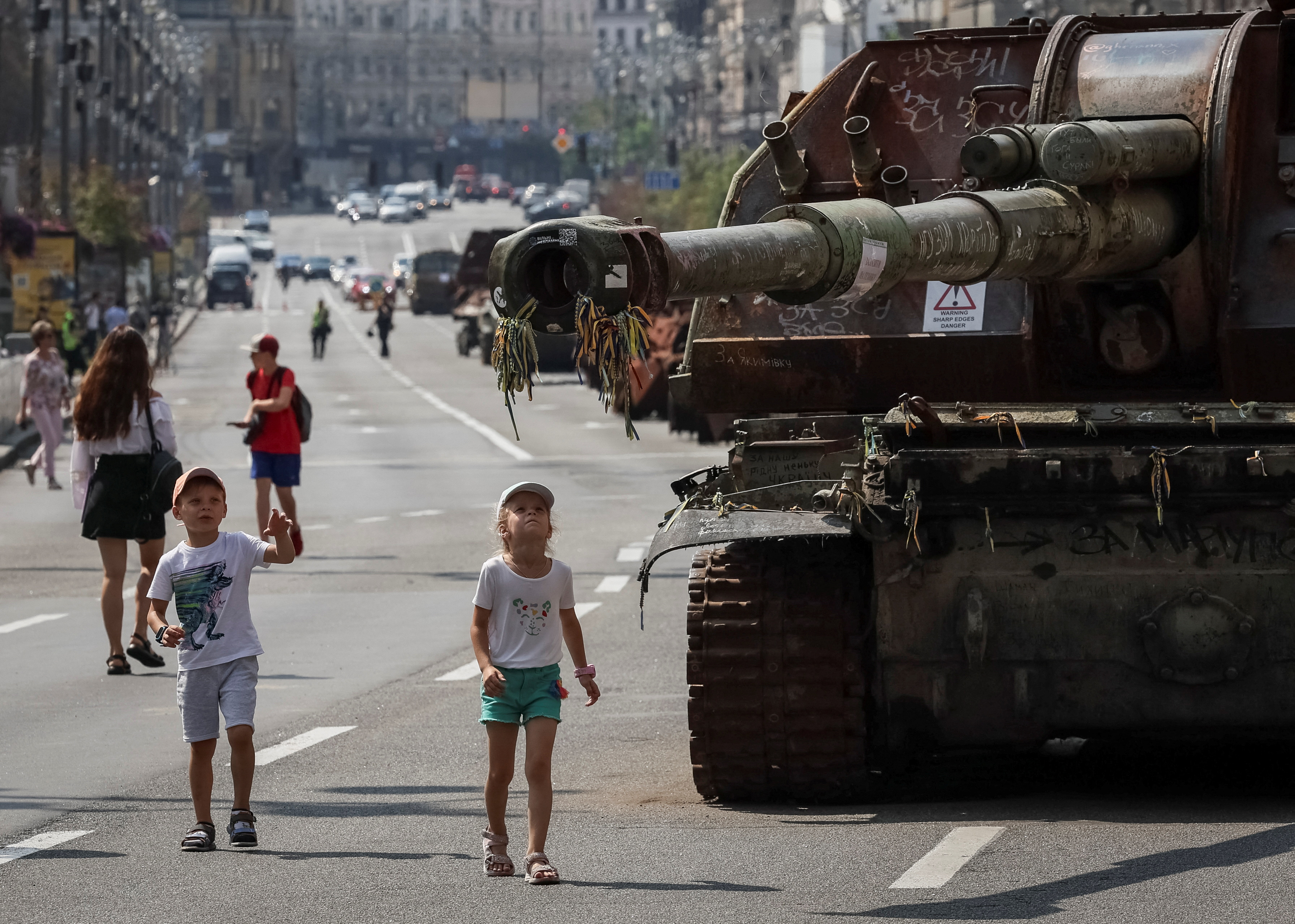 Children playing near a captured Russian tank on display in Kyiv. The Russian military vehicles are lined up along the road.