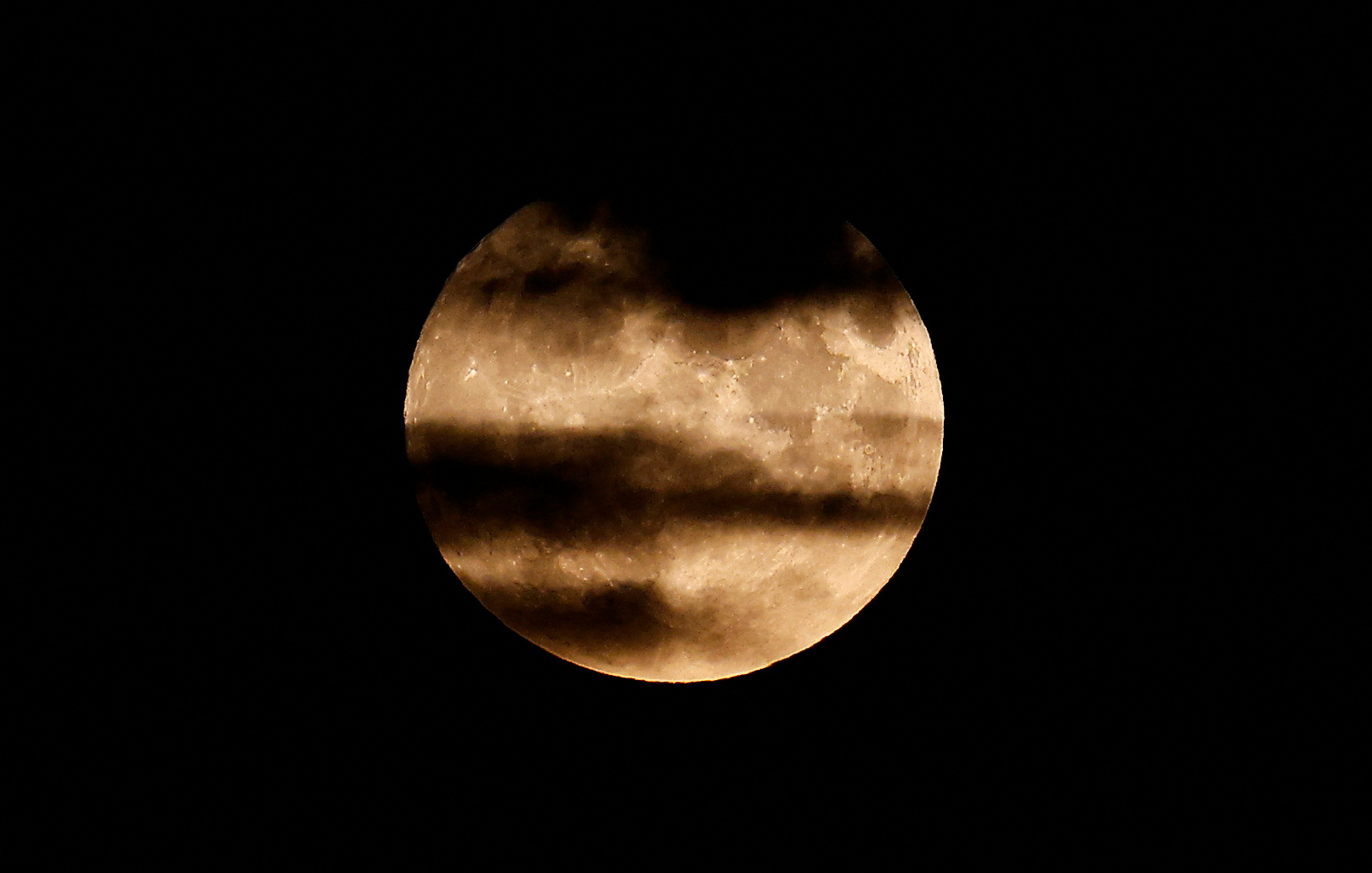 An aircraft flies over London and in front of the the super moon