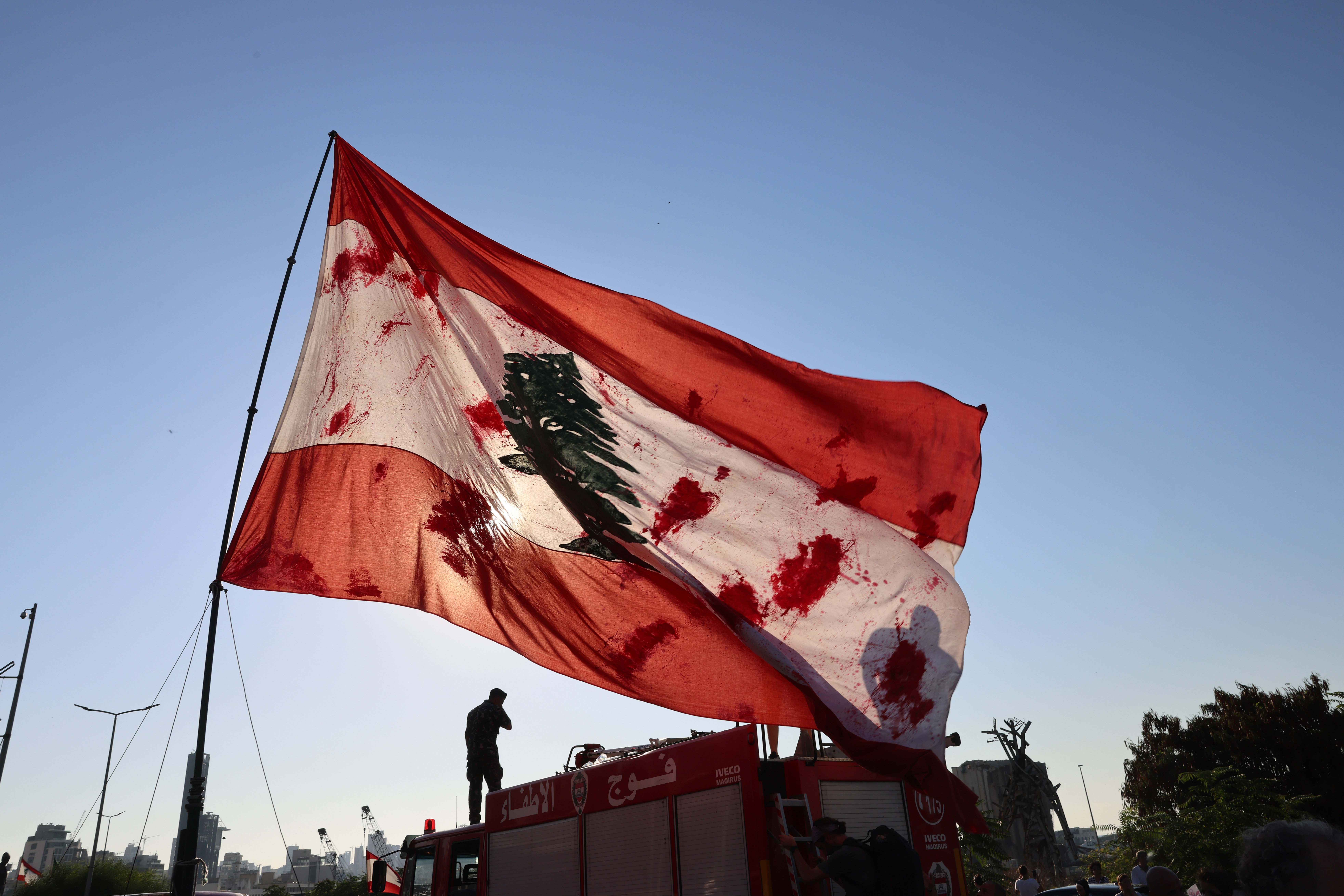 Protesters lift flags and placards depicting the victims of the 2020 Beirut port blast