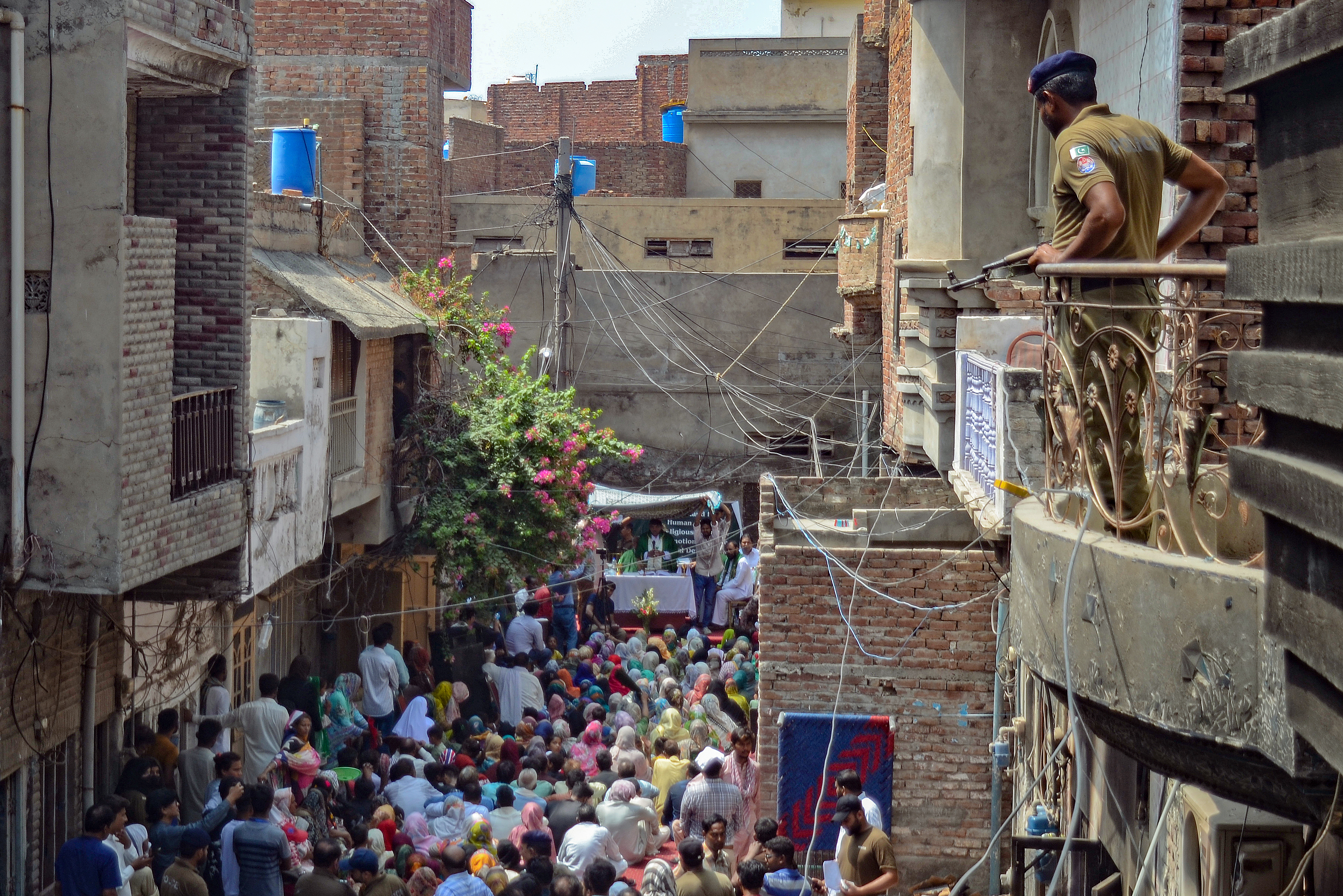 A policeman stands guard as Christians attend a Sunday Service near the torched Saint John Church in Jaranwala on the outskirts of Faisalabad on August 20, 2023