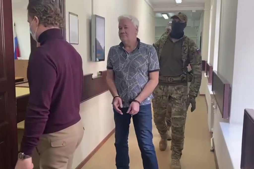 In this handout photo taken from video released by Lefortovo District Court, Robert Shonov walks escorted by officers to the court room at the Lefortovo District Court in Moscow, Russia, Thursday, May 18, 2023. Robert Shonov, a Russian national who worked at the now-closed U.S. consulate in Vladivostok for more than 25 years, was detained in the far eastern city and is facing charges of "cooperation on a confidential basis with a foreign state, international or foreign organization." The charge carries punishment of up to eight years in prison. (Lefortovo District Court via AP)