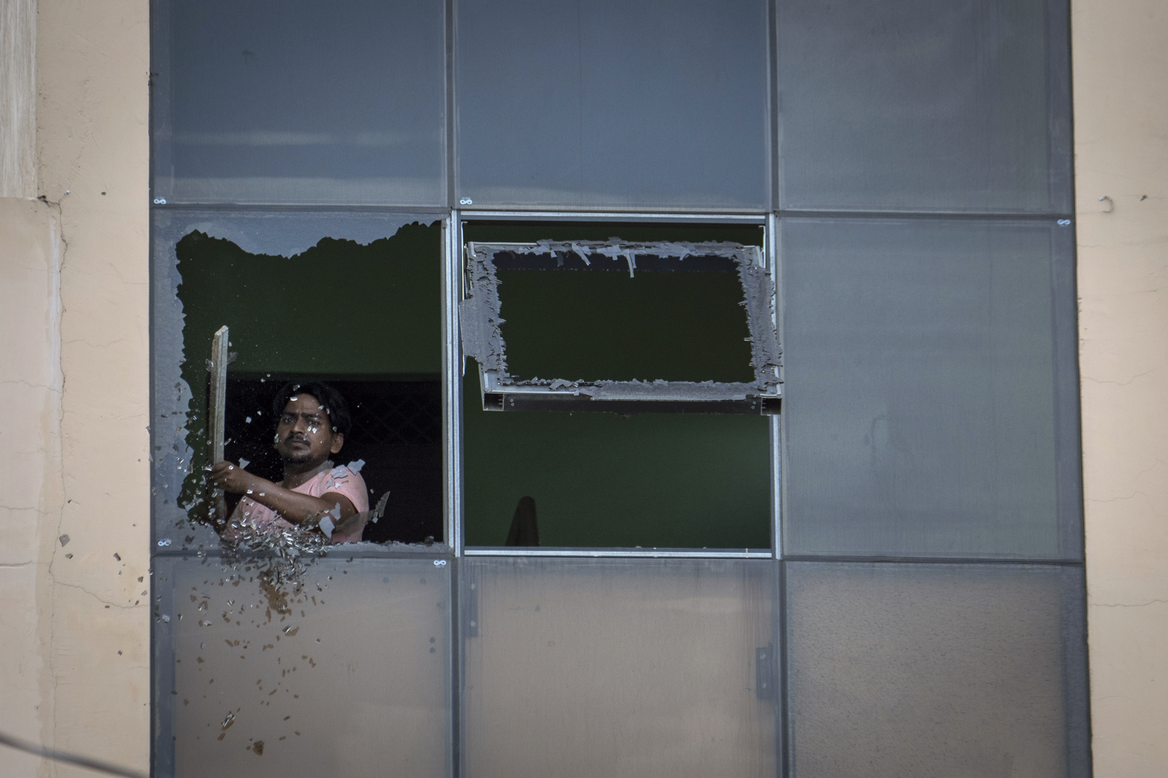 A worker removes broken glass from a window of a restaurant