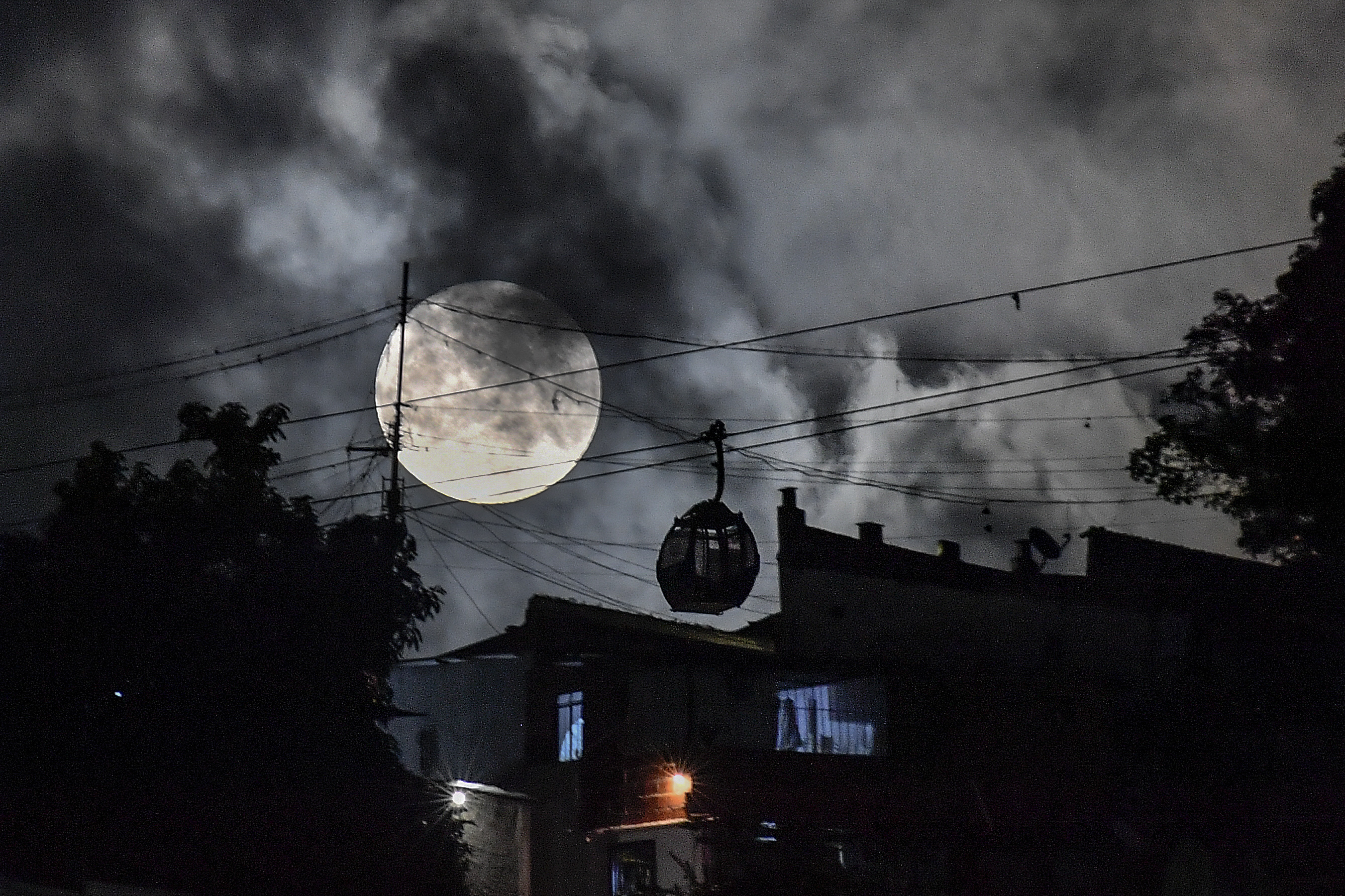 A cable car moves towards the San Agustin neighborhood as a supermoon rises in the sky of Caracas, Venezuela, Tuesday, Aug. 1, 2023