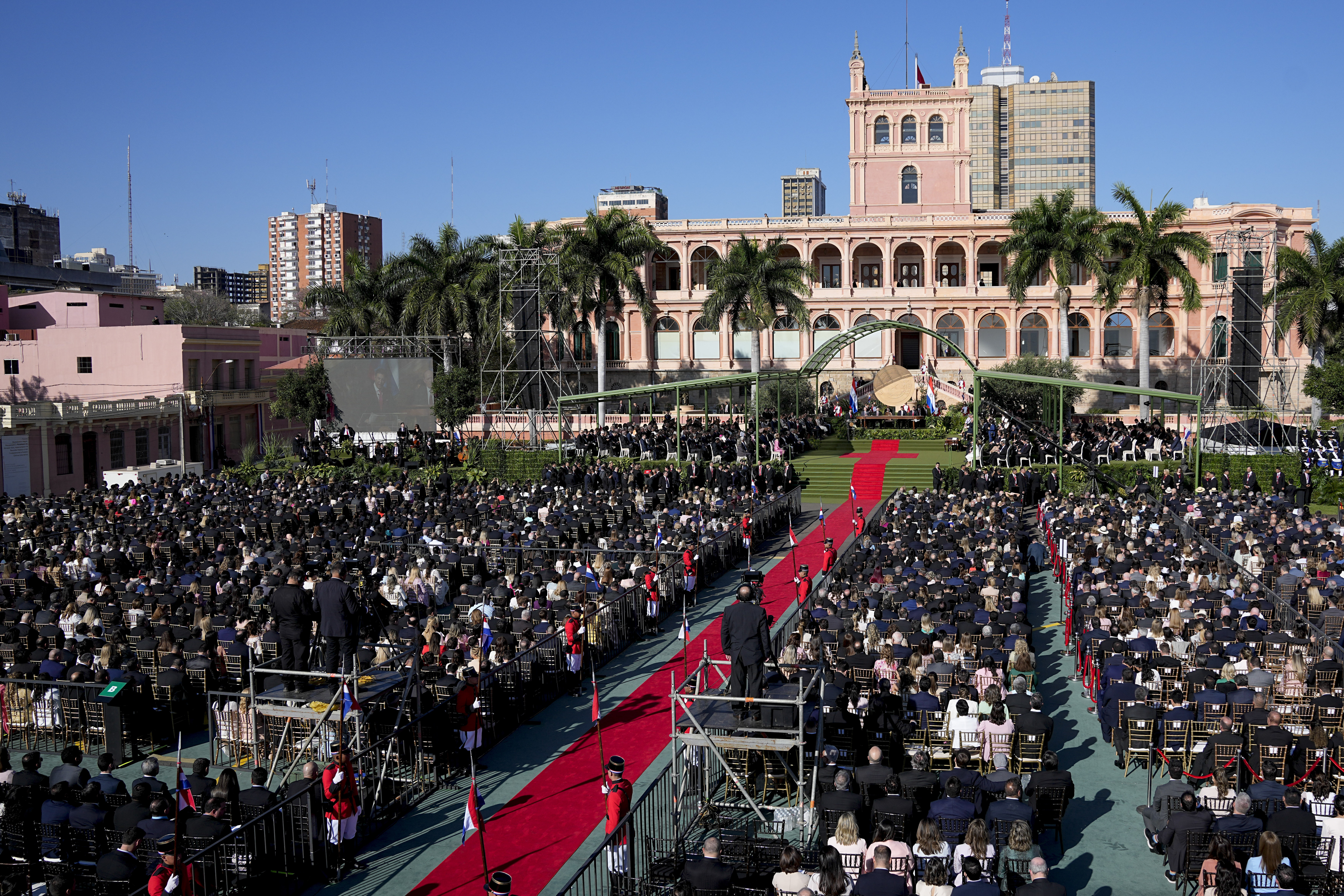A red carpet stretches from the presidential palace through a crowd of onlookers.