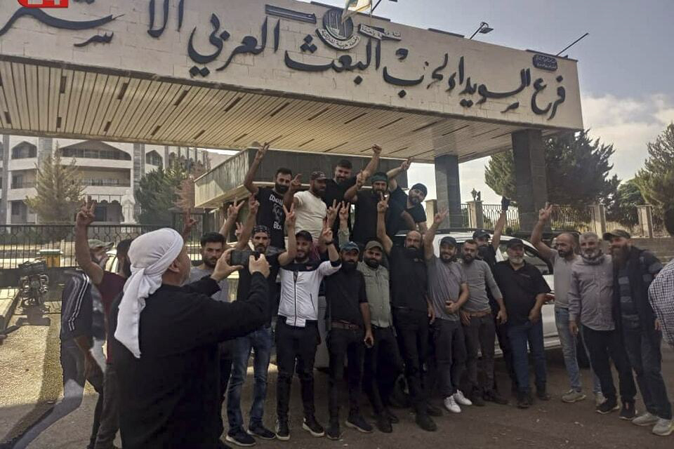 In this photo released on Sunday, Aug. 27, 2023, by Suwayda24, people stage a protest outside the Baath party building in the southern city of Sweida, Syria. Anti-government protests have rocked south Syria for the past week. Demonstrators initially took to the streets over surging inflation but are now calling for the ouster of President Bashar Assad, echoing the beginnings of a 2011 uprising that sparked Syria's brutal civil war. (Suwayda24 via AP)