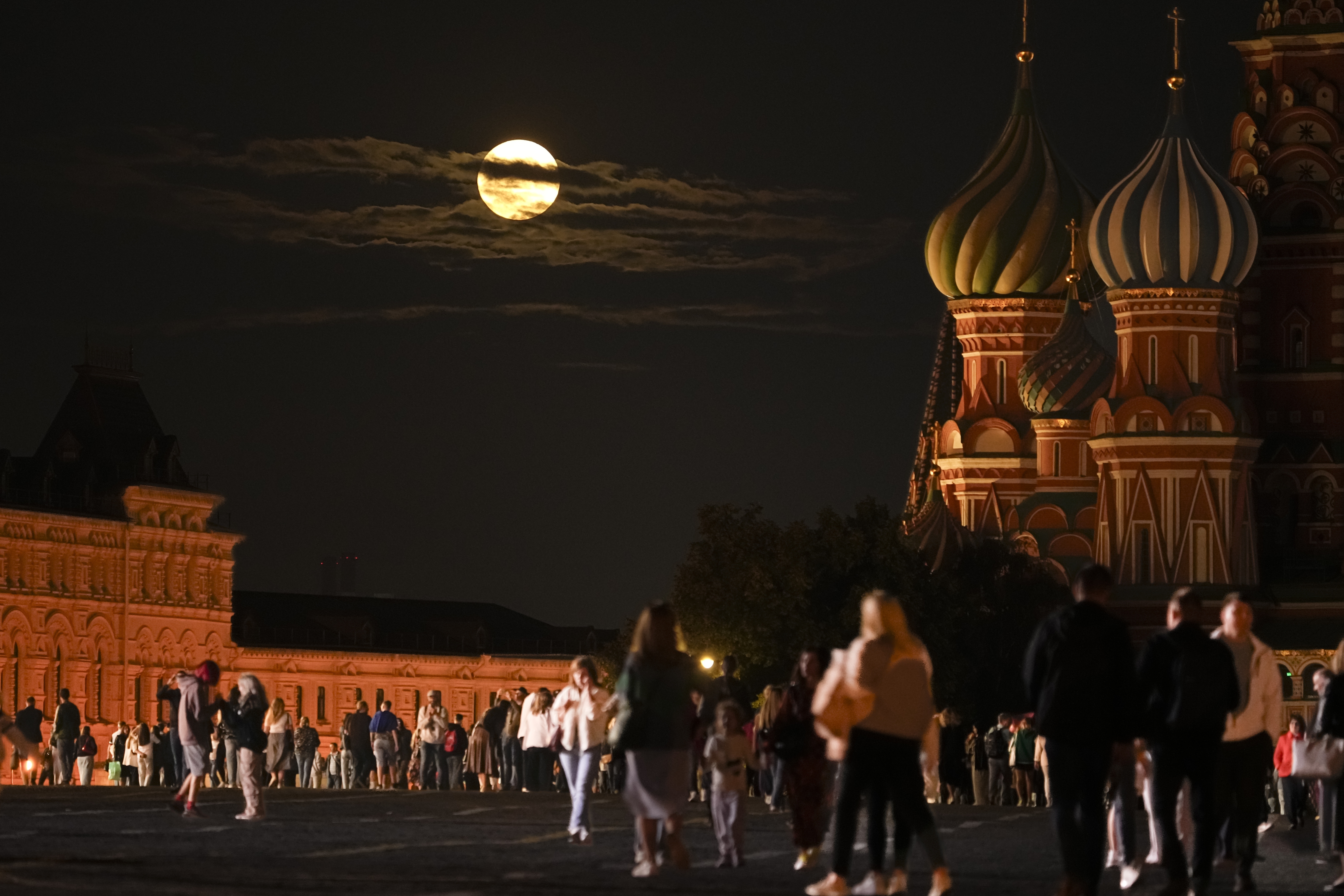 he August Super Blue Moon sets behind a historical building and the St. Basil's Cathedral