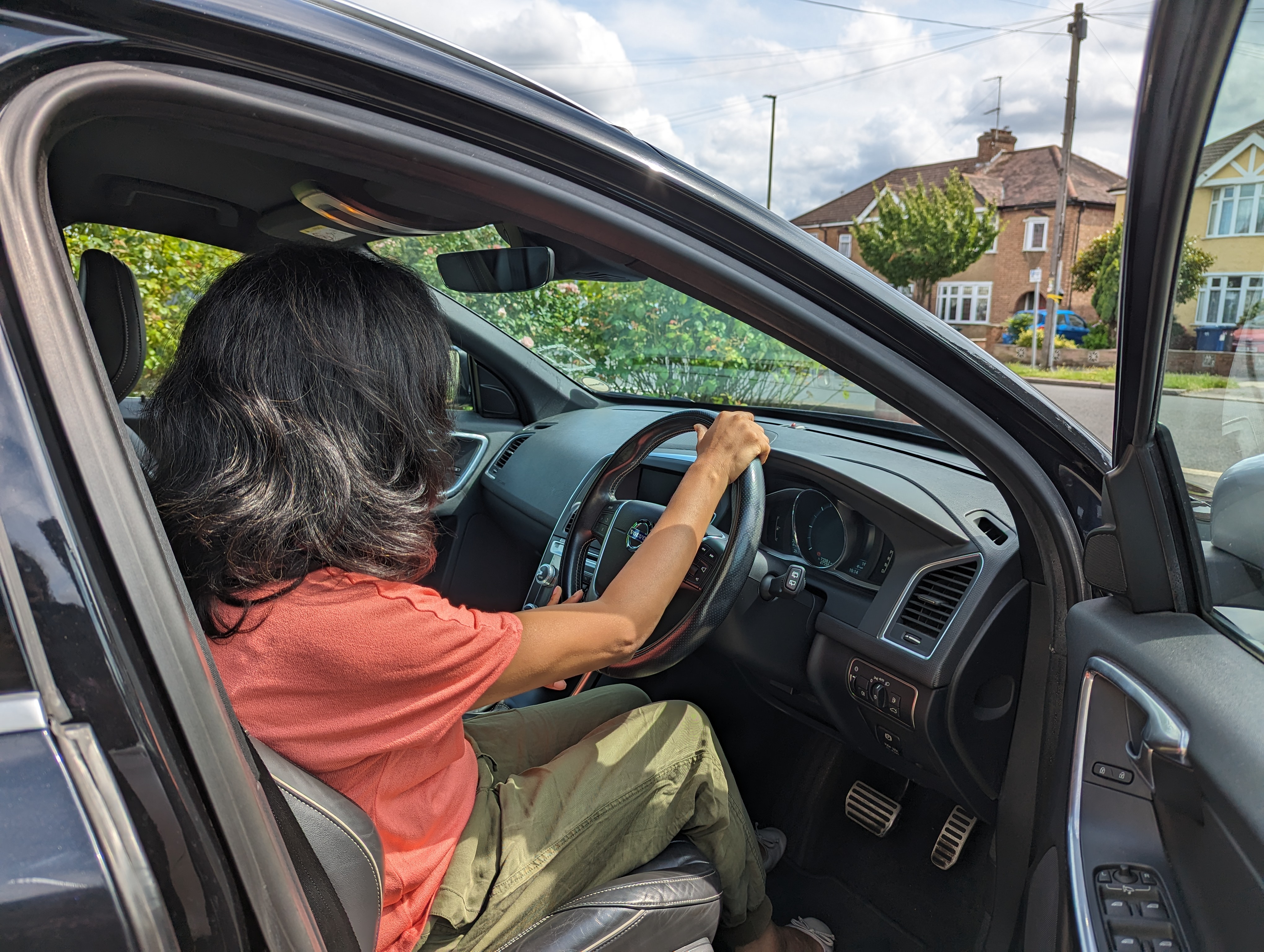 A photo of someone sitting in the front seat of a car holding the steering wheel.