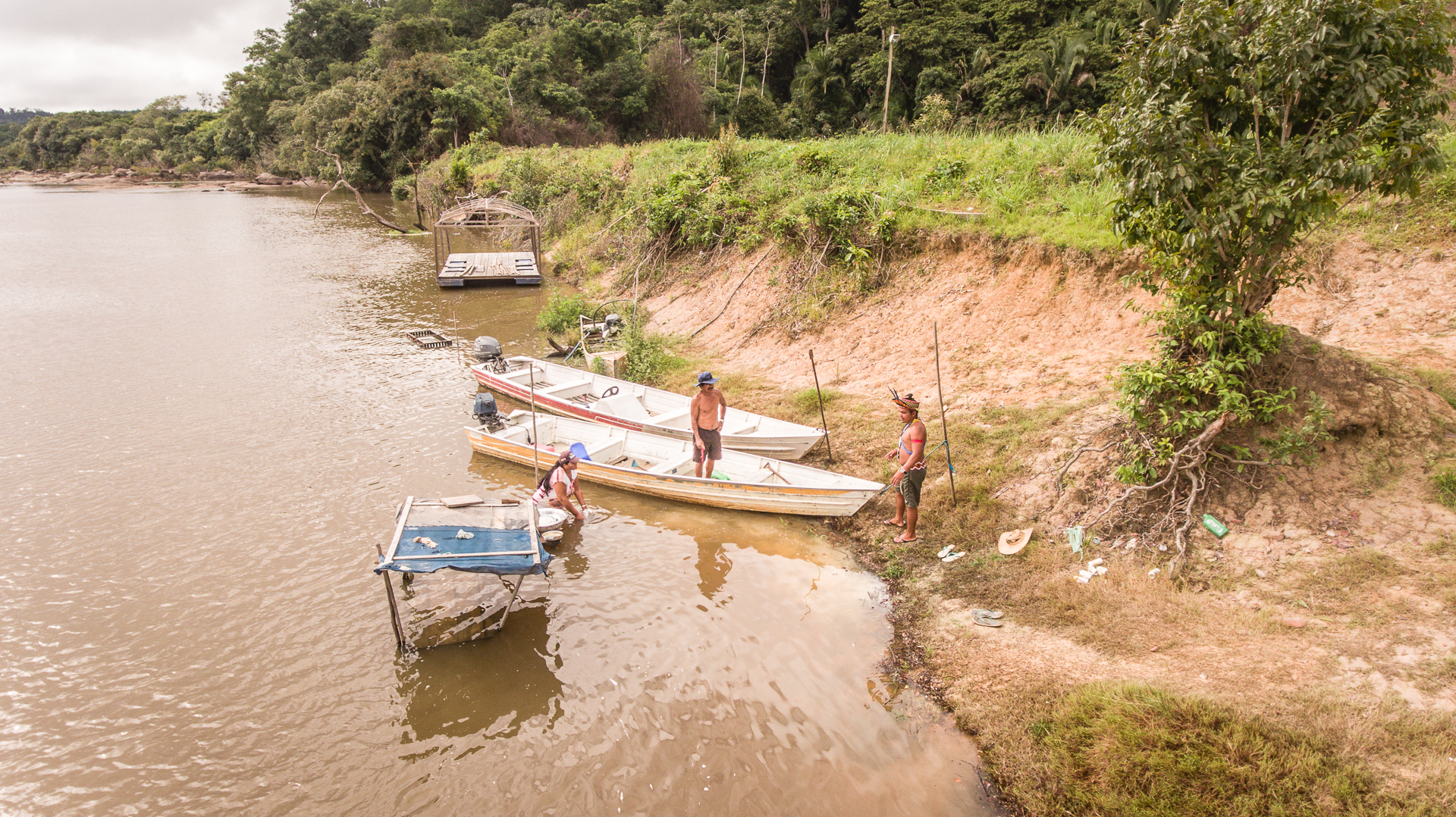 Francisco Juruna, Socorro Juruna and Jardel Juruna stand in the shallow waters of the Xingu River with their canoes.