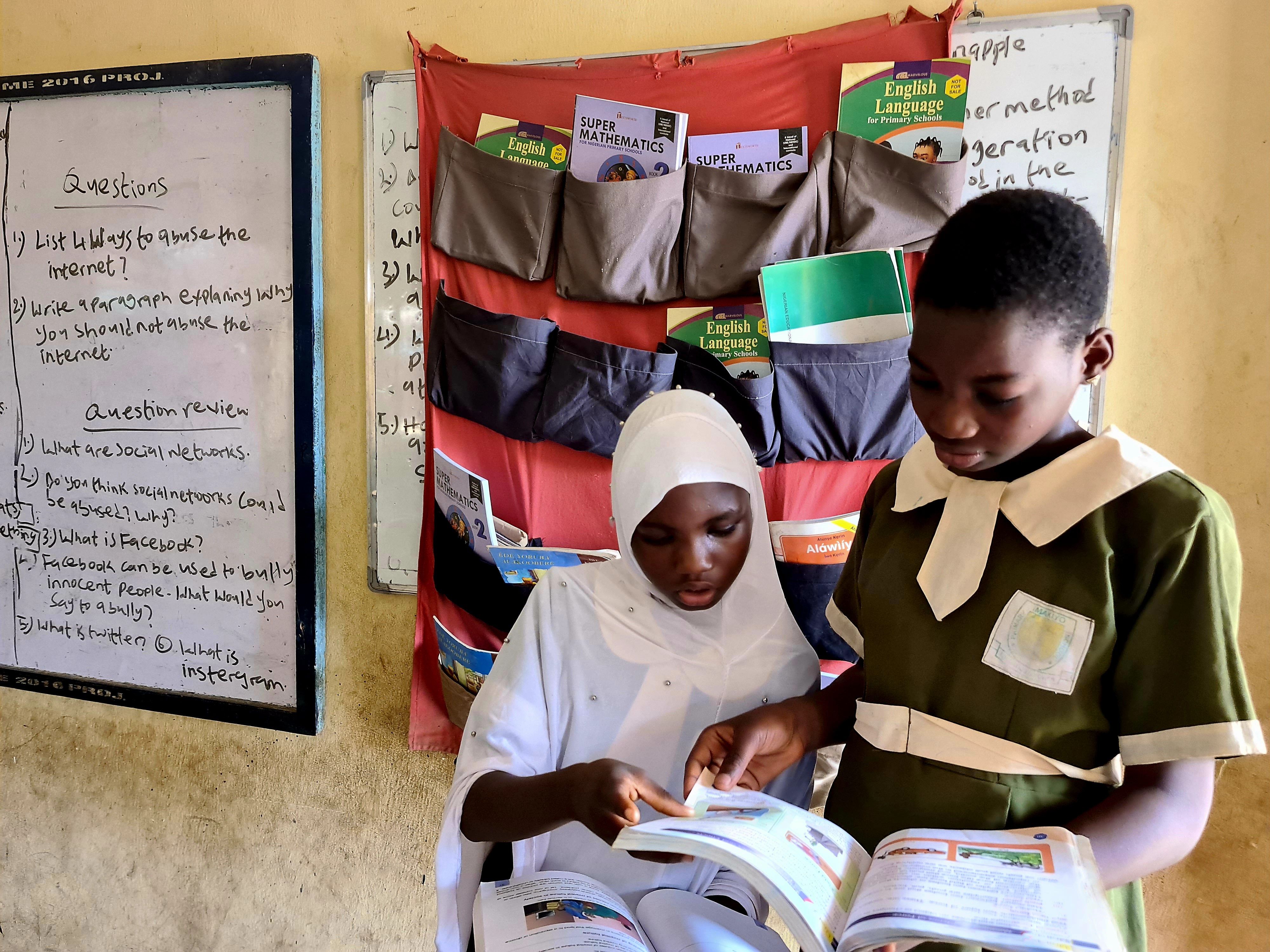 Two students read in front of the hanging library at a school in Lagos