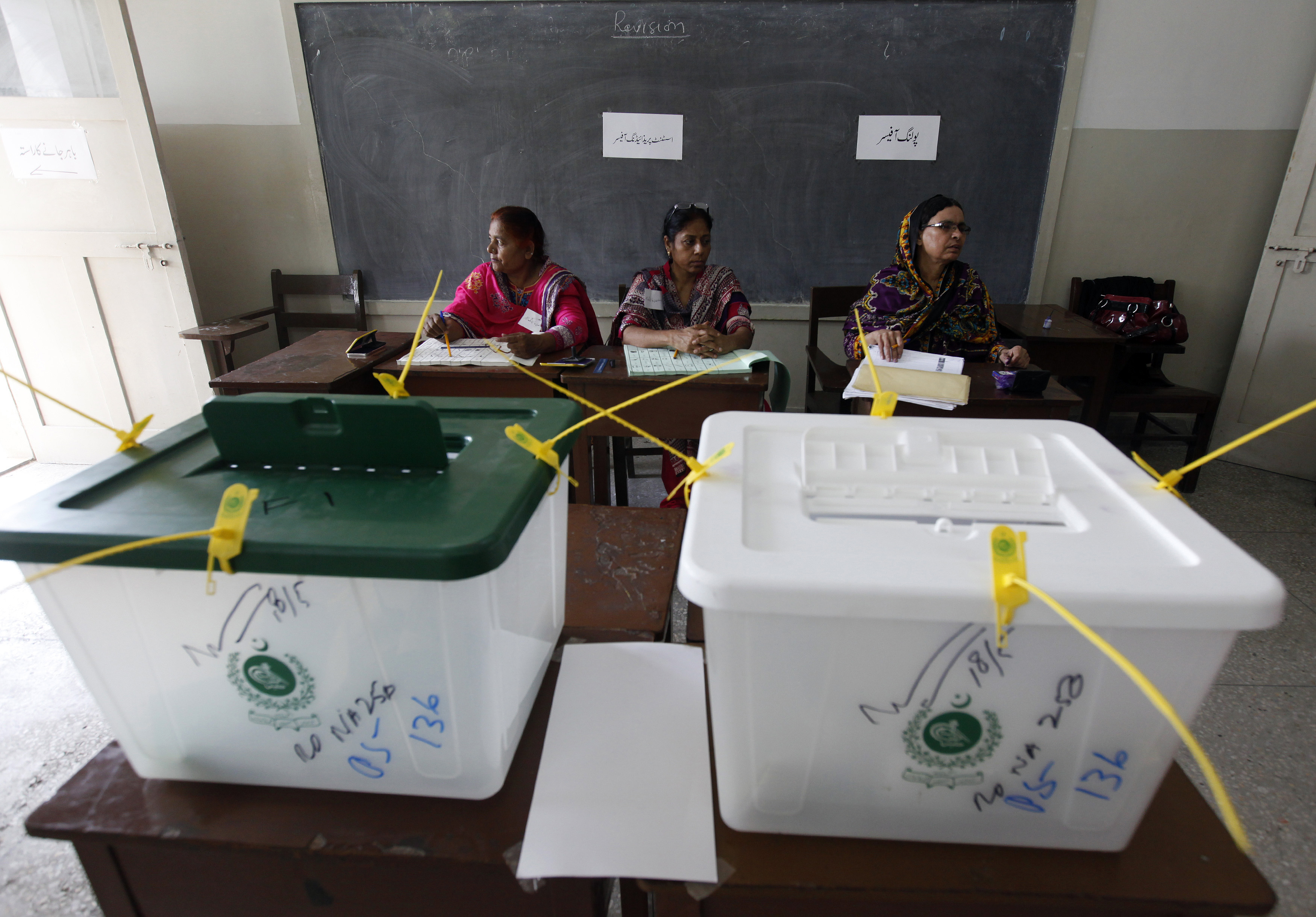 Election officials wait for voters inside a polling station during a re-polling for the general elections in Karachi.