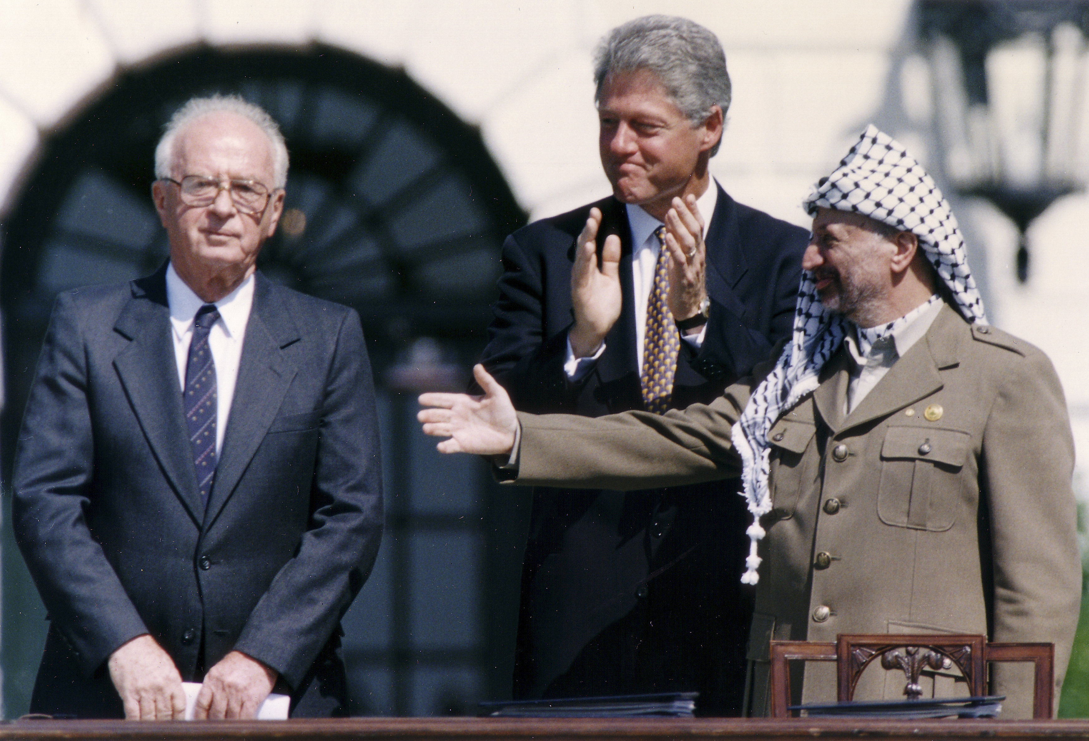 PLO Chairman Yasser Arafat (R) gestures to Israeli Prime Minister Yitzhak Rabin (L), as U.S. President Bill Clinton stands between them, following their handshake after the signing of the Israeli-PLO peace accord, at the White House in Washington September 13, 1993. REUTERS/Gary Hershorn (UNITED STATES - Tags: POLITICS)