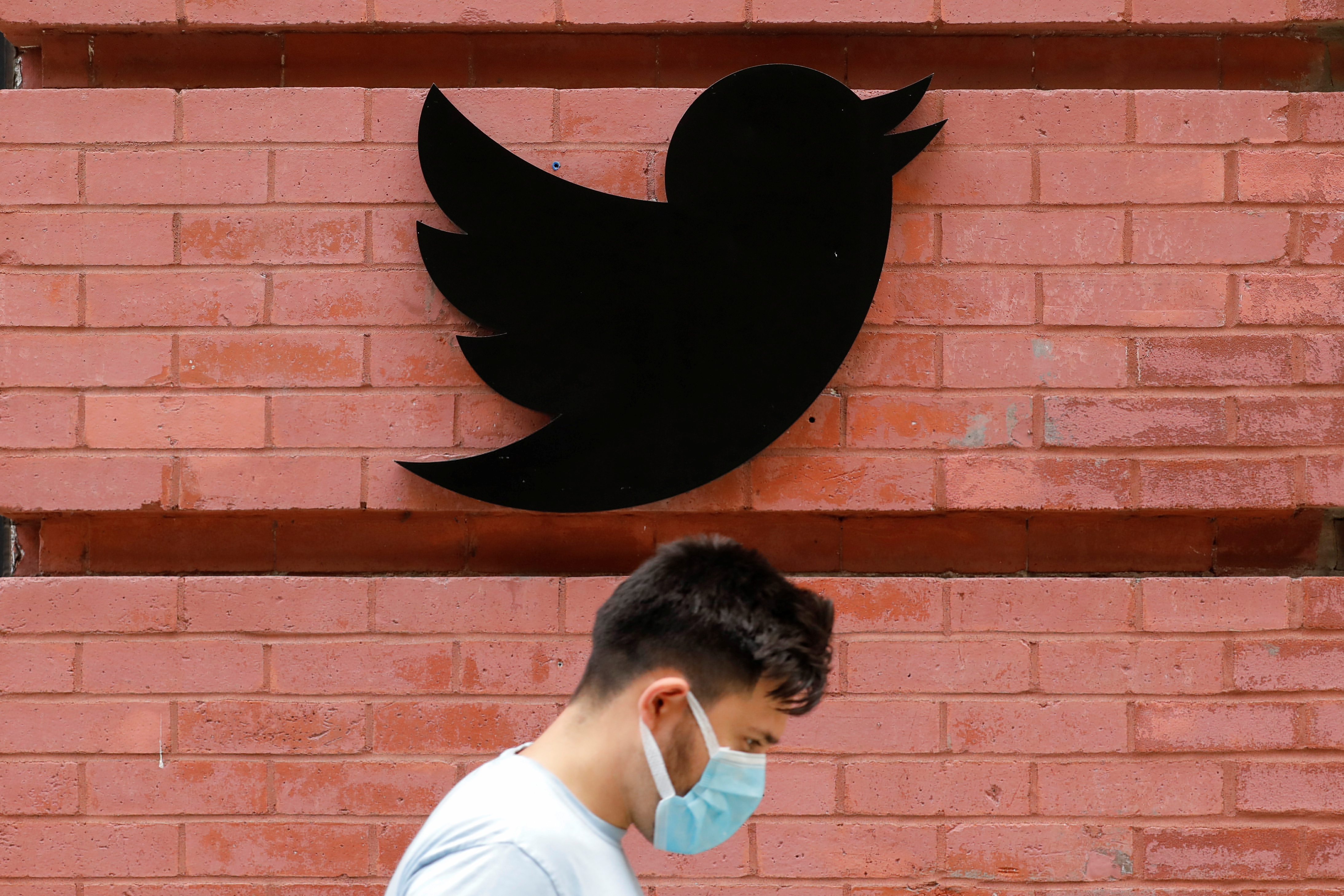 A person in a mask walks by the New York Twitter offices after they announced they will close their re-opened offices effective immediately in response to updated CDC guidelines during the outbreak of the coronavirus disease (COVID-19) in Manhattan, New York City, U.S., July 29, 2021.