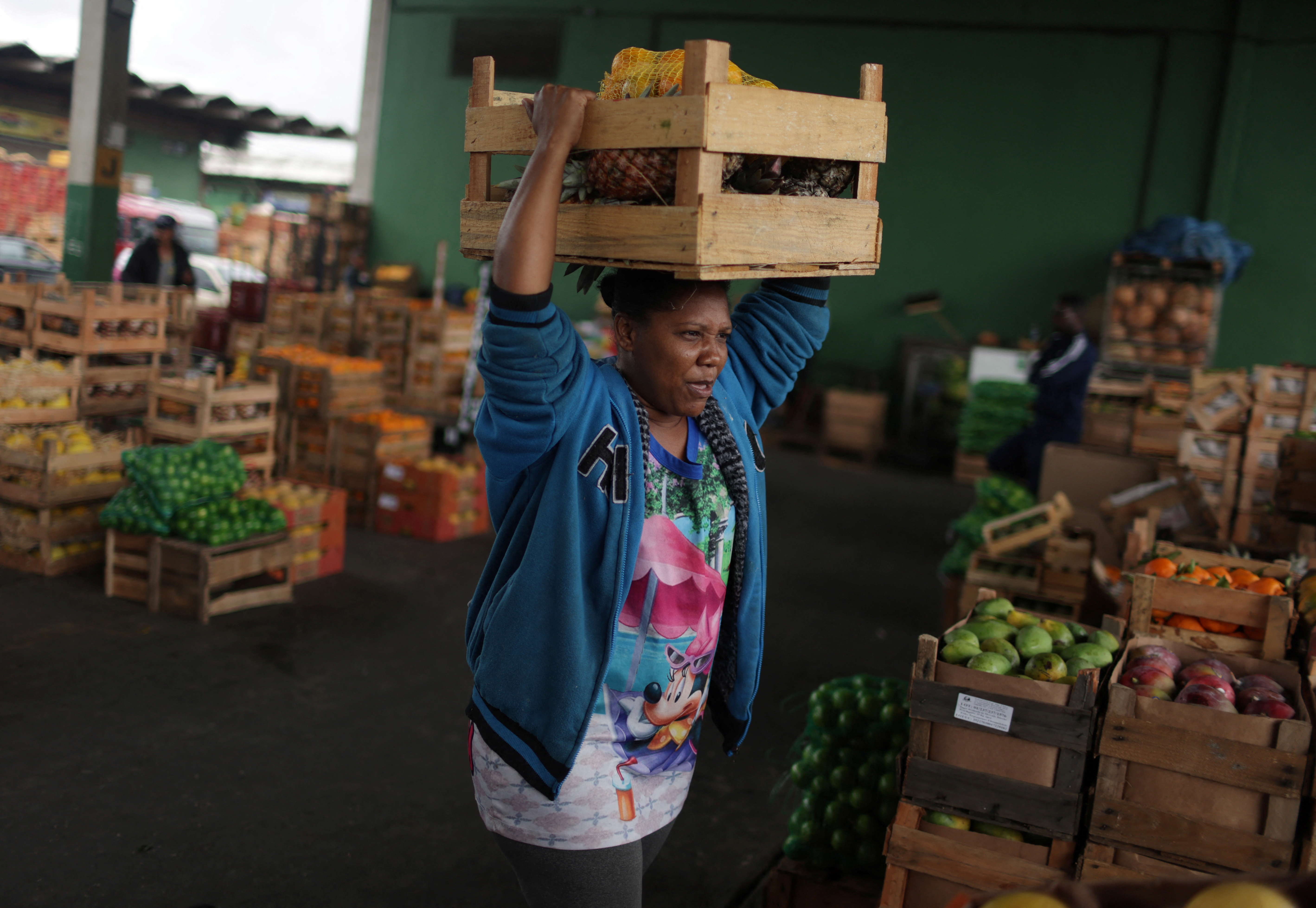 Carla dos Santos Feliciano, 38, carries a box of fruit and vegetables donated by merchants at the CEASA supply centre in Rio de Janeiro, Brazil, August 30, 2022