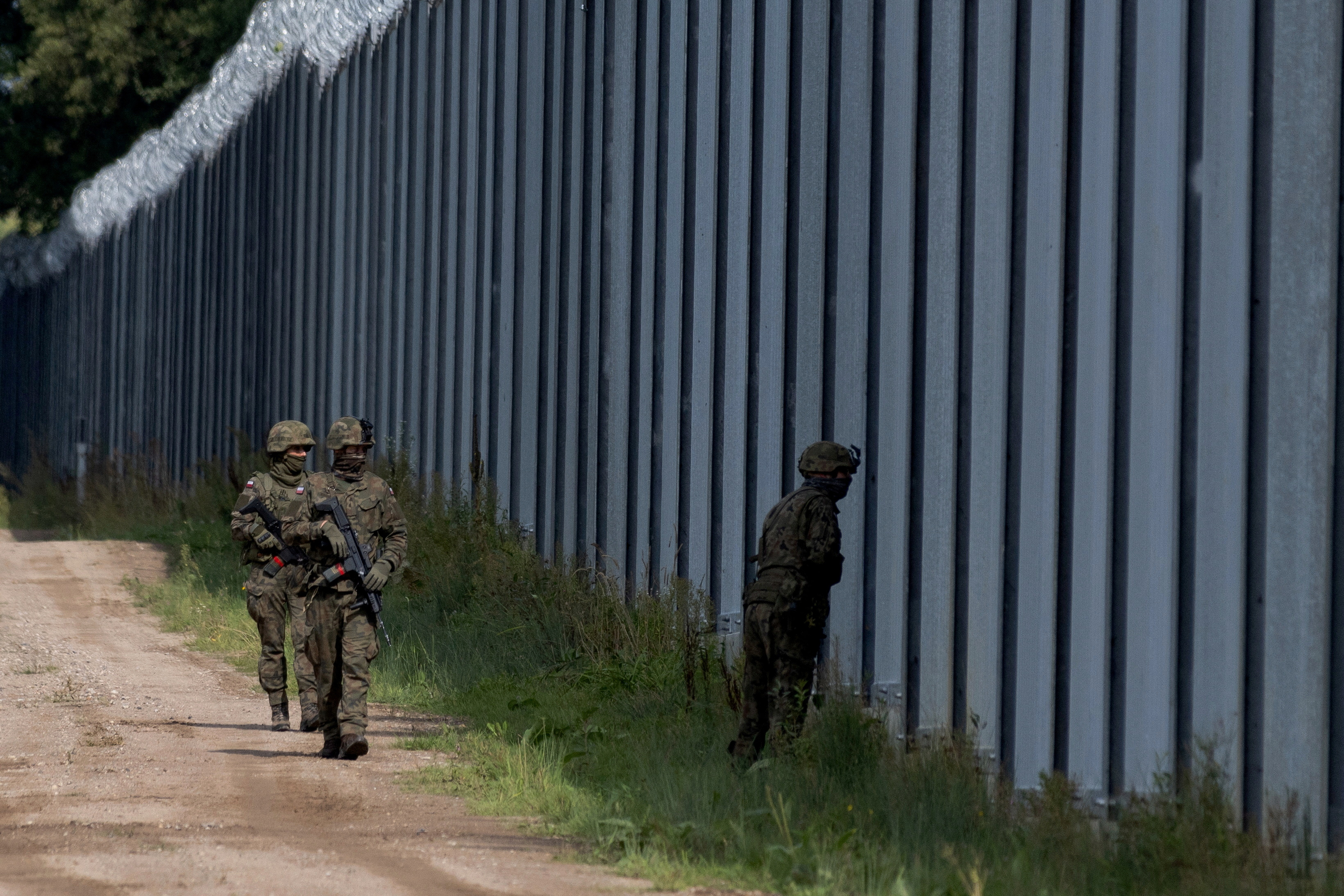 Polish soldiers patrol along the border fence on the Polish-Belarusian border in Usnarz Gorny, Poland
