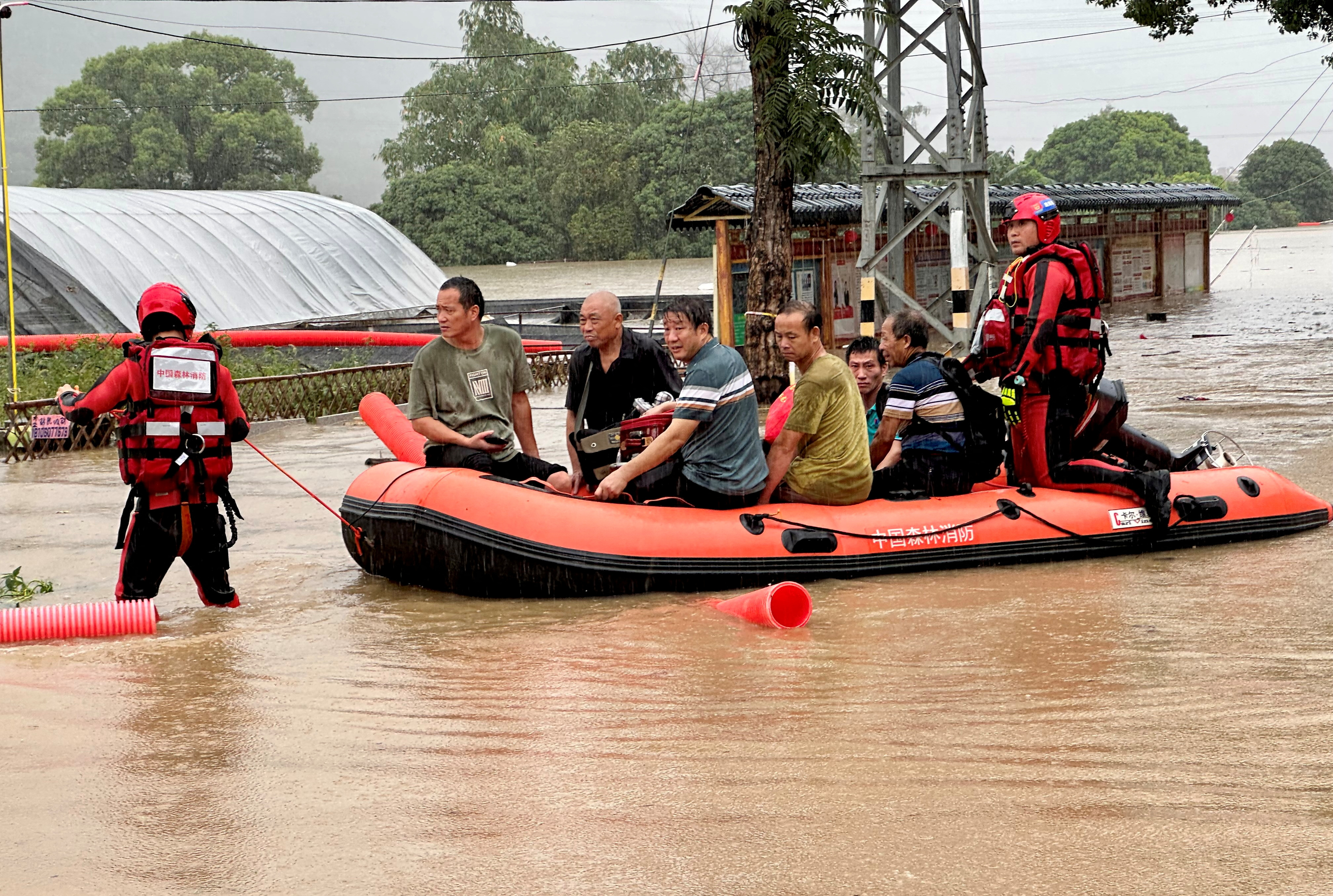 Rescue workers evacuate residents in an inflatable dinghy. The water is brown and about thigh deep.