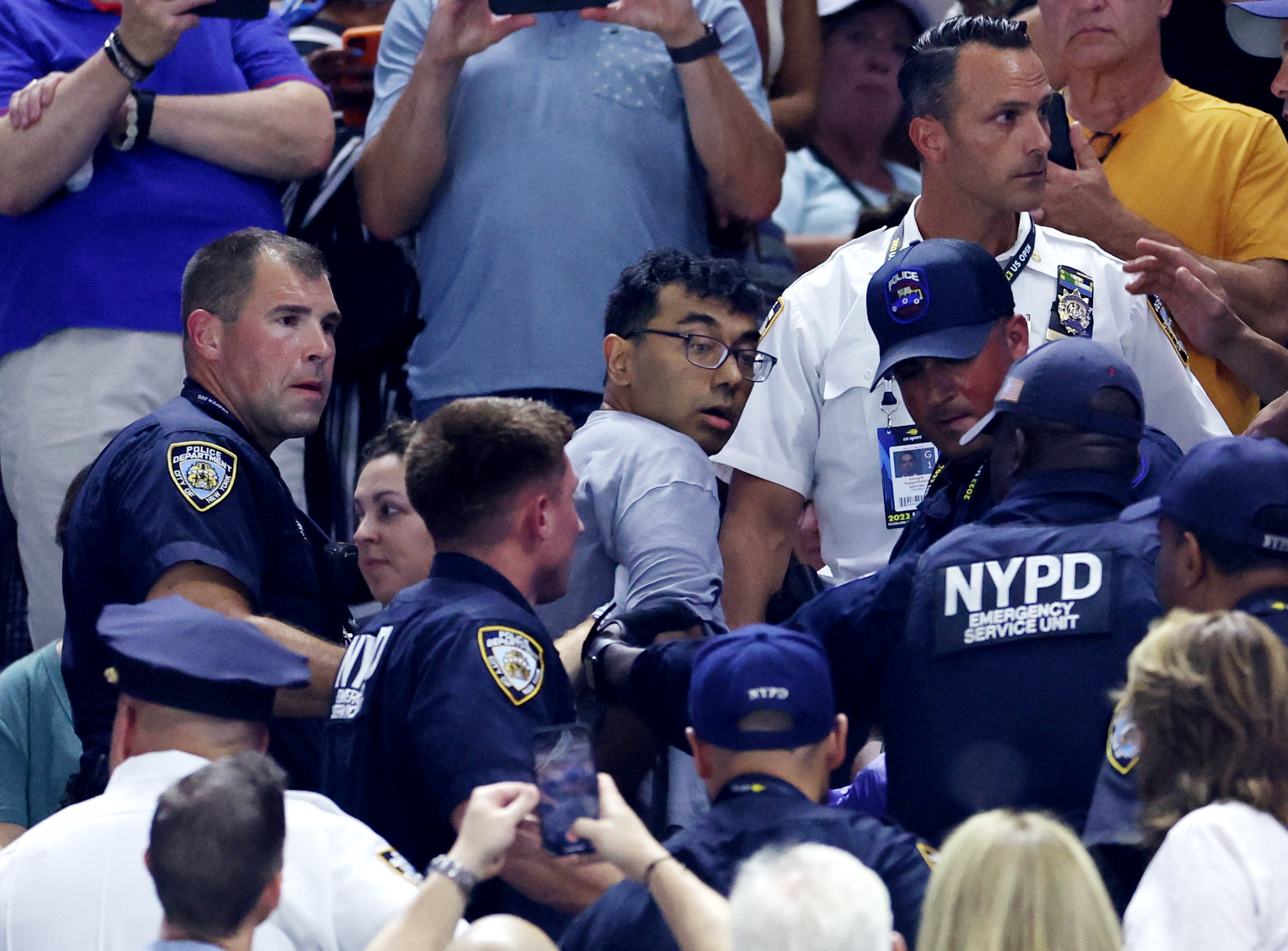 A demonstrator is being removed from the stadium by New York City Police Department (NYPD) officers during the semi final match between Czech Republic's Karolina Muchova and Coco Gauff of the U.S.