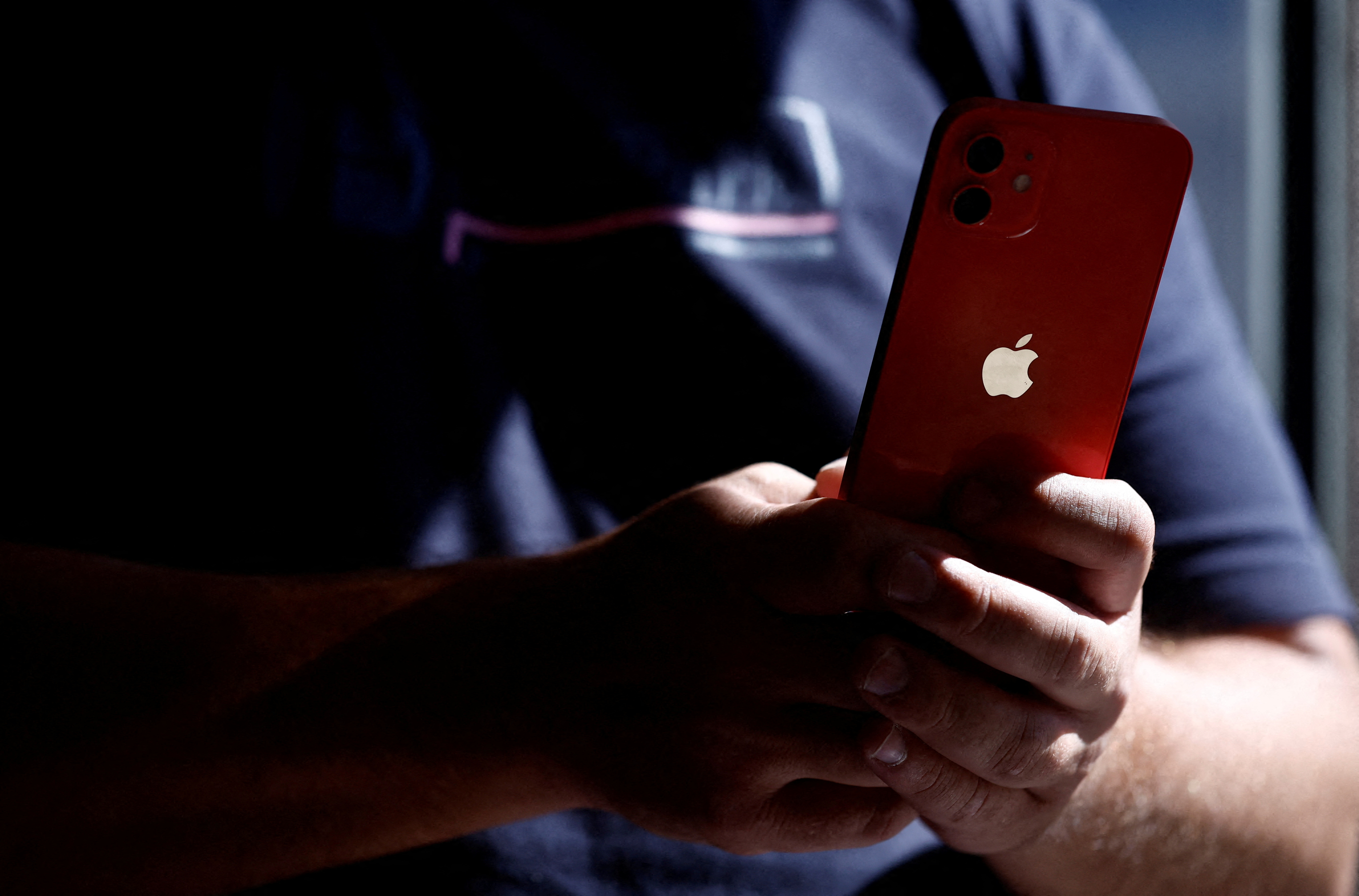 A man poses with an Apple iPhone 12 in a mobile phone store in Nantes, France, September 13, 2023.