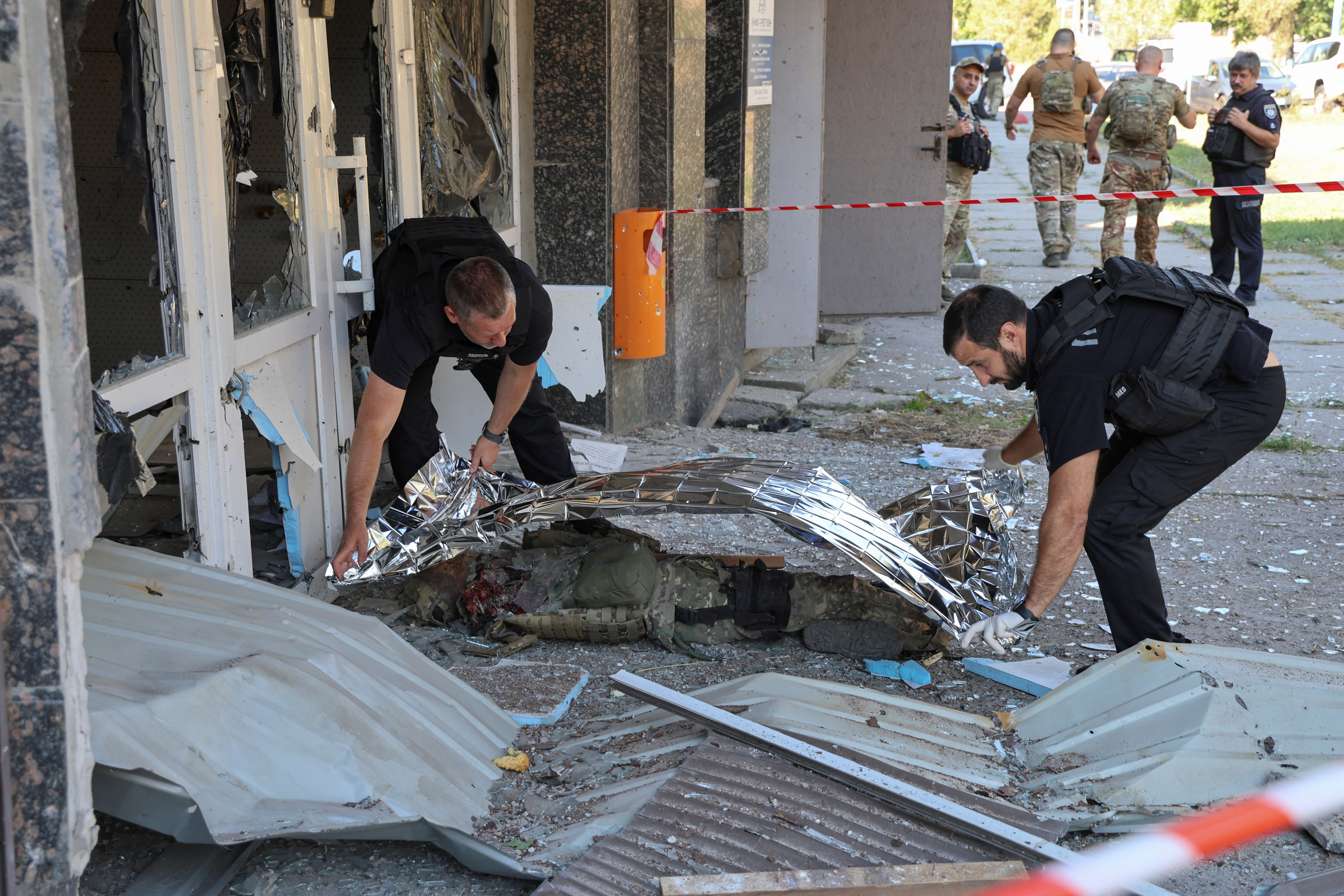 Police officers cover the body of their mate Andrii Tarchynskyi, who was killed during a Russian military strike