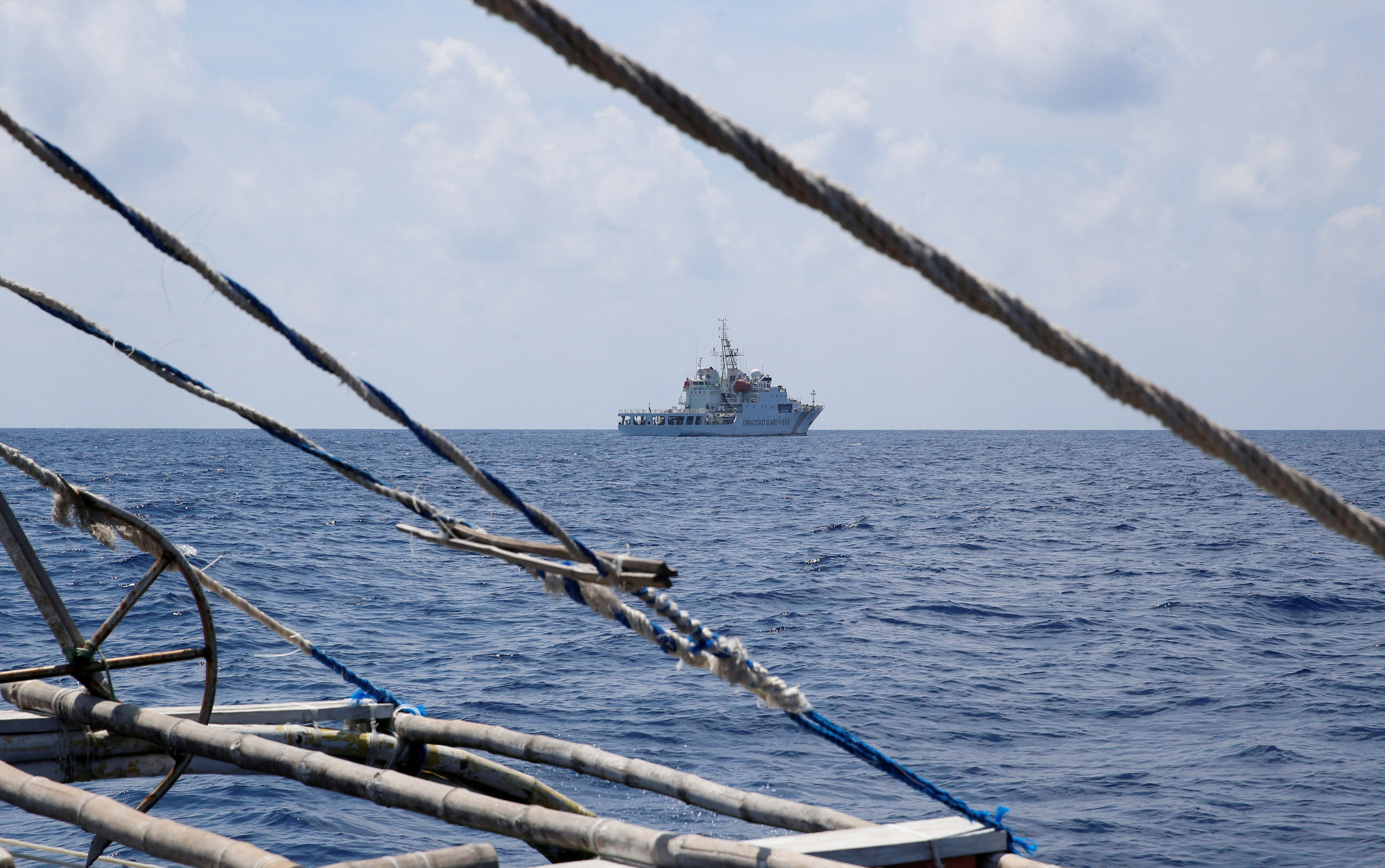 A Chinese coast guard ship seen through rigging on a Philippines fishing boat near Scarborough Shoal in the South China Sea